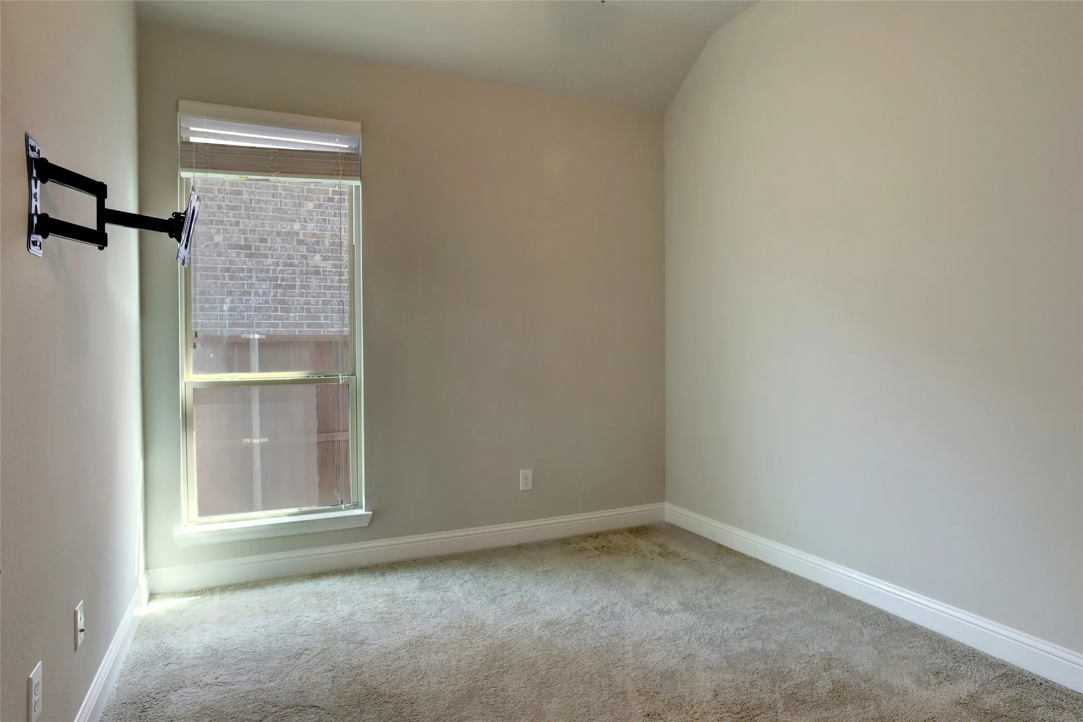 Carpeted room with a single window featuring blinds and a white frame