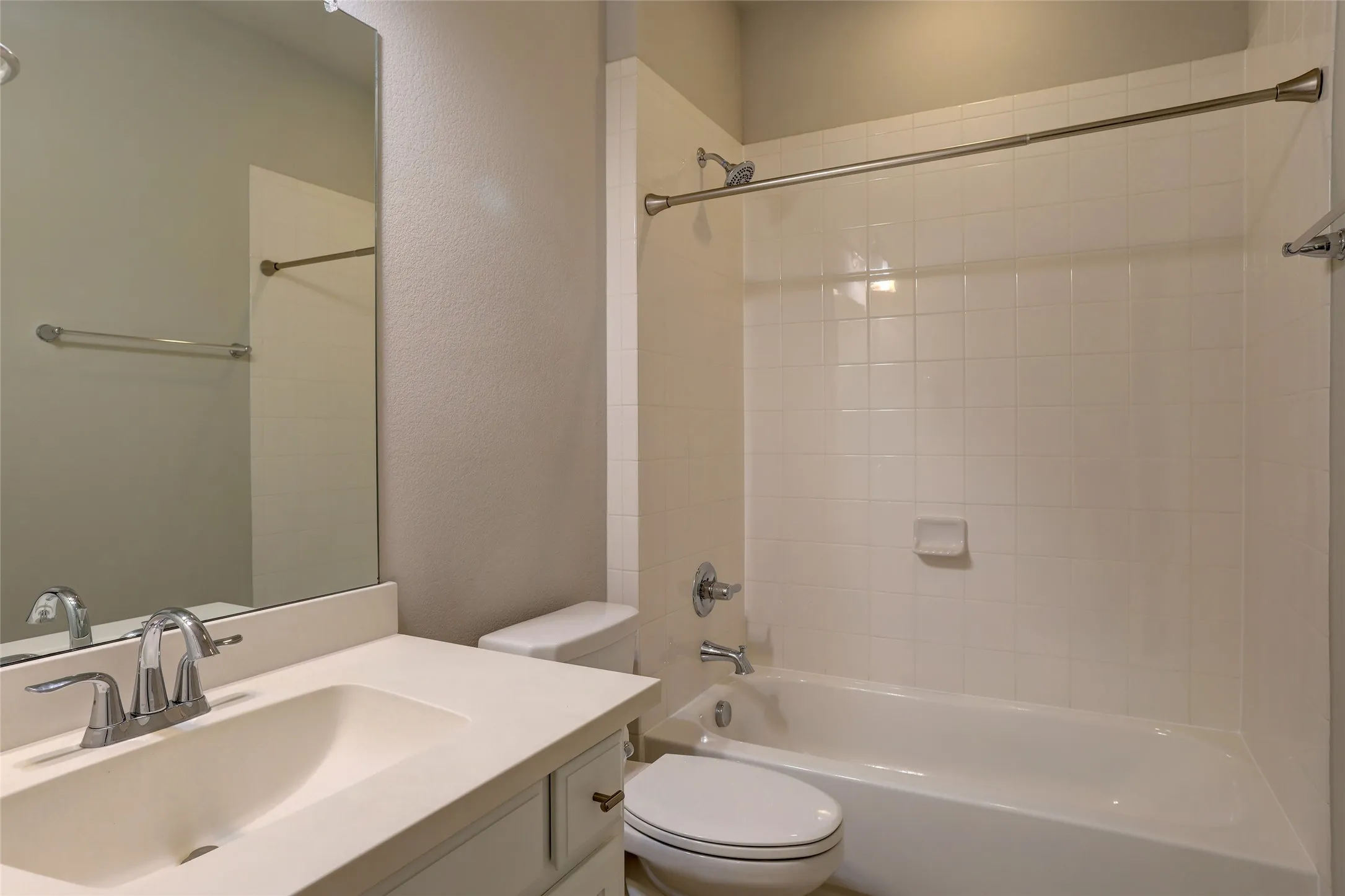 Full bathroom featuring a single-basin vanity with an integrated sink, polished chrome faucet, and a large wall-mounted mirror