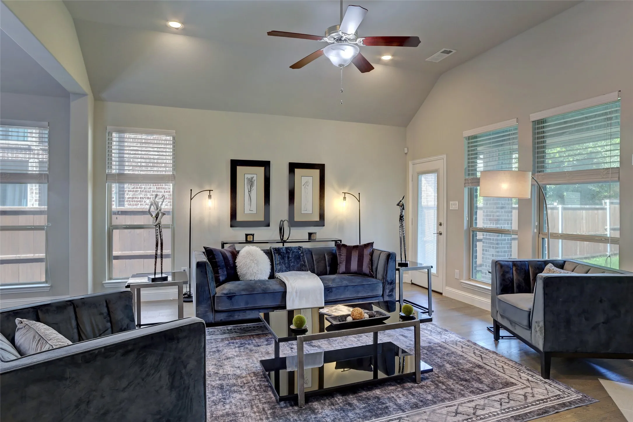 Living area featuring vaulted ceilings, recessed lighting, a ceiling fan, multiple windows with blinds, and wood-finish flooring