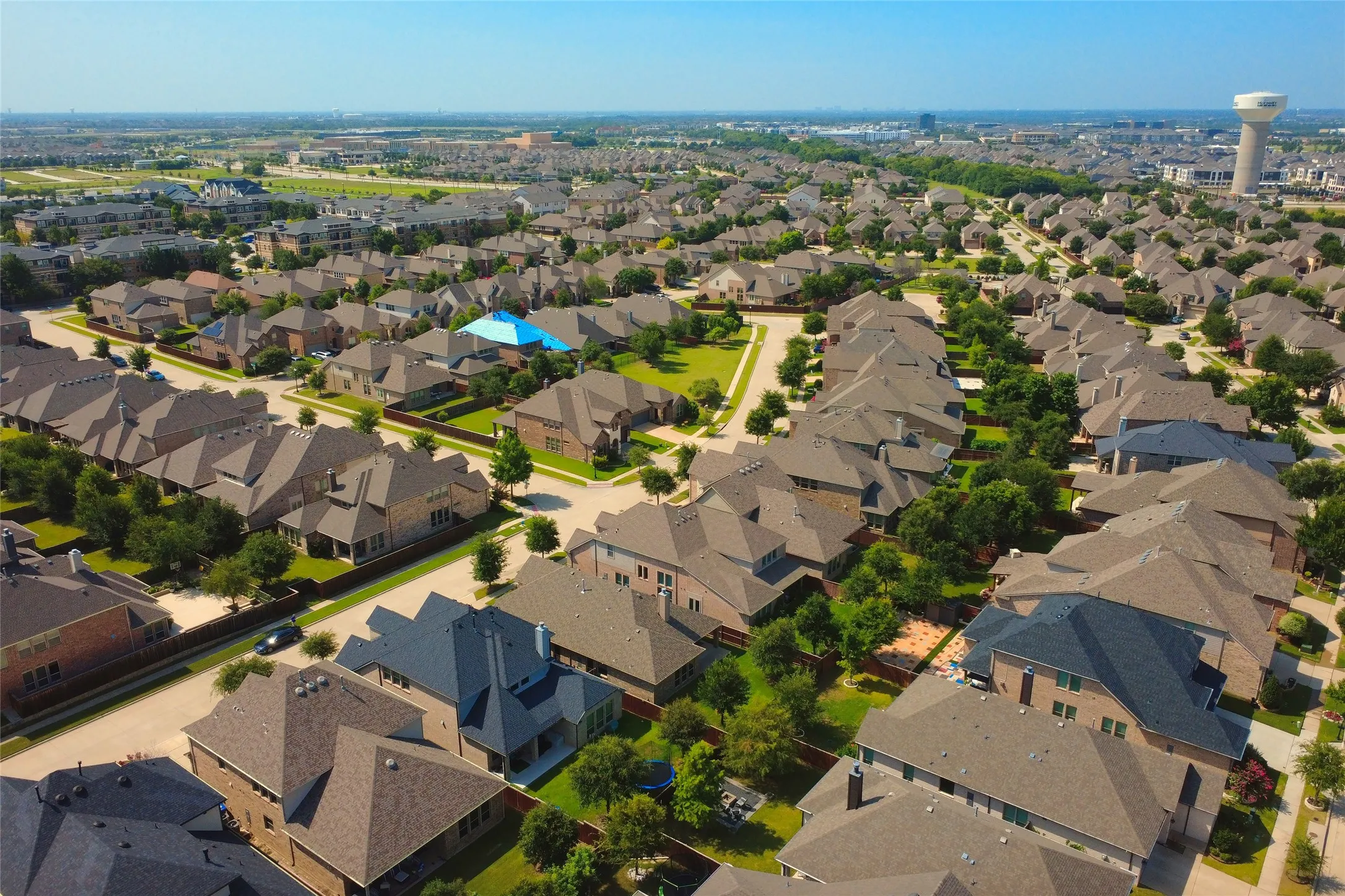 Aerial perspective showcasing a residential development featuring numerous single-family homes with pitched roofs and manicured landscaping