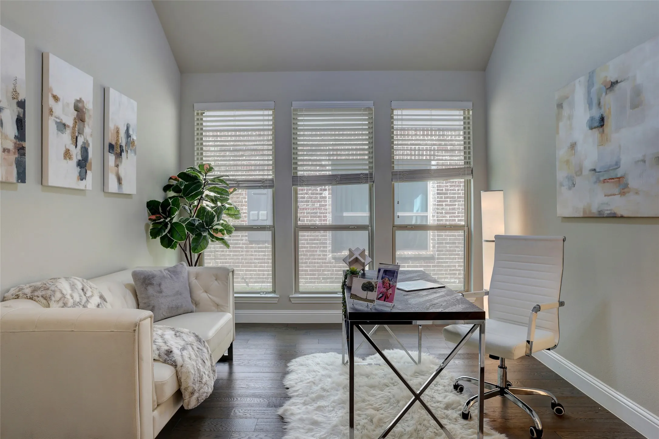 Dedicated room featuring dark wood-finish flooring, light-toned walls, and a trio of windows with horizontal blinds