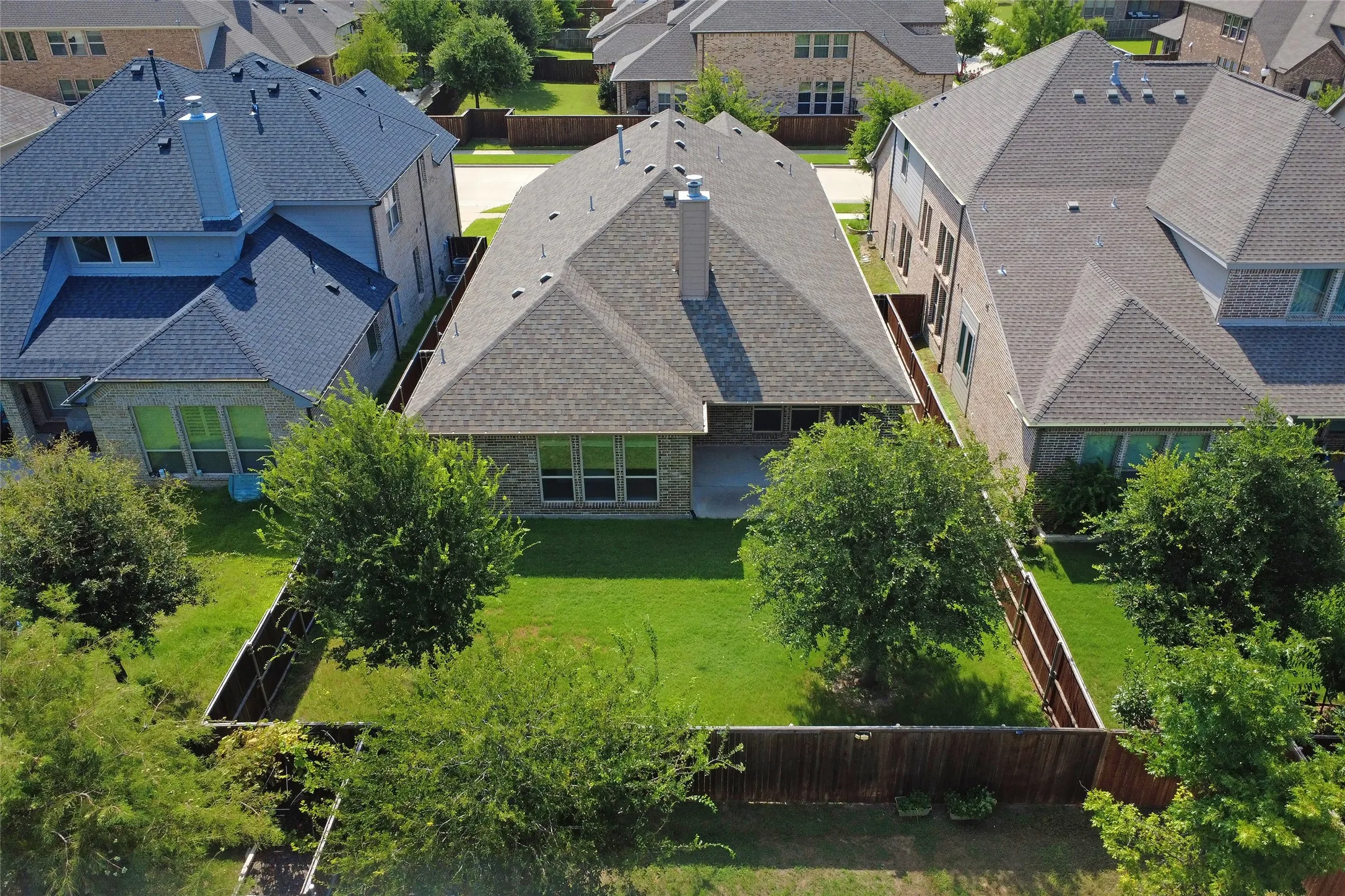 Expansive backyard featuring a manicured lawn, mature trees, and a full privacy fence