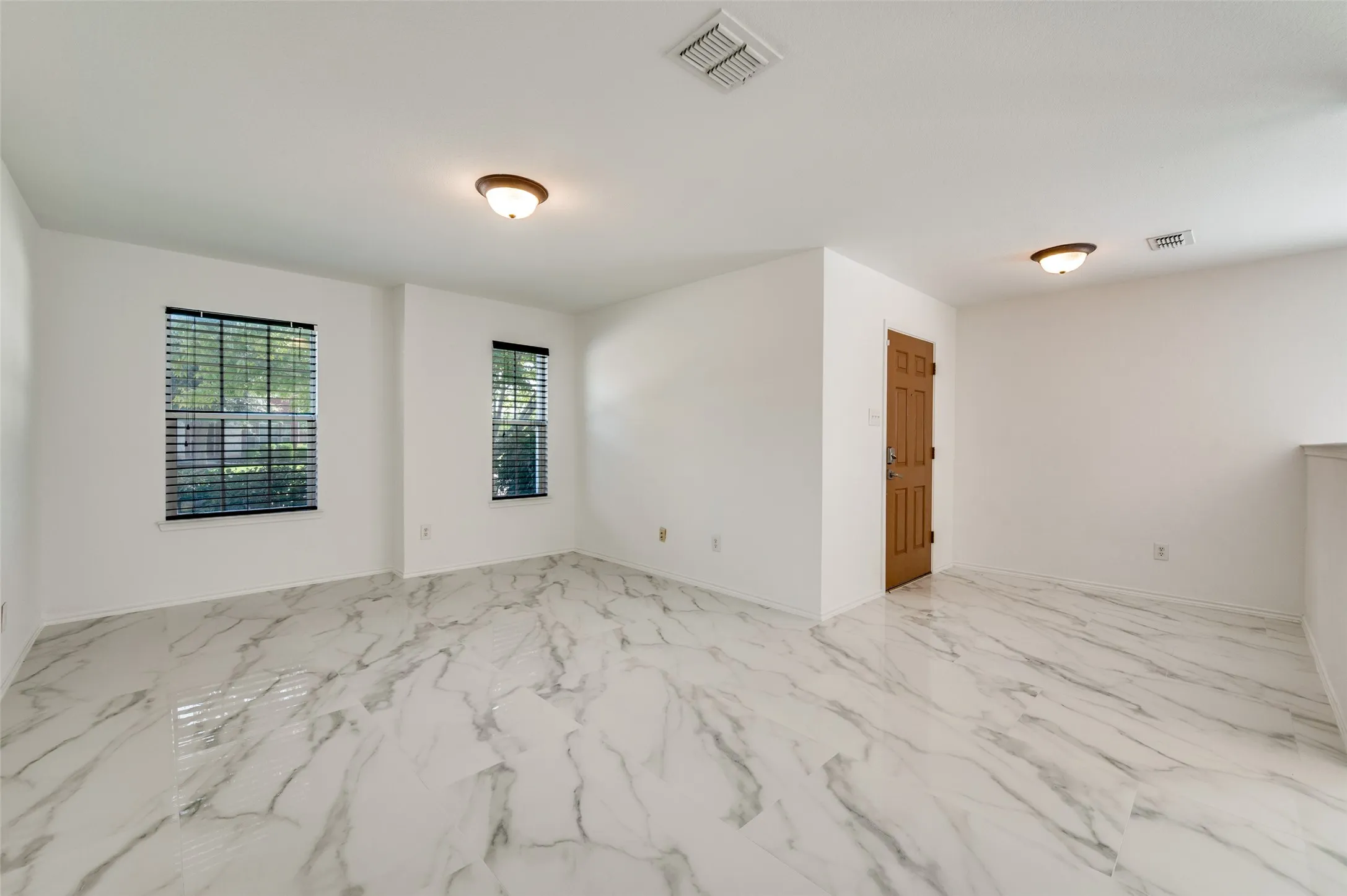 Spacious room featuring white walls and marble-look tile flooring