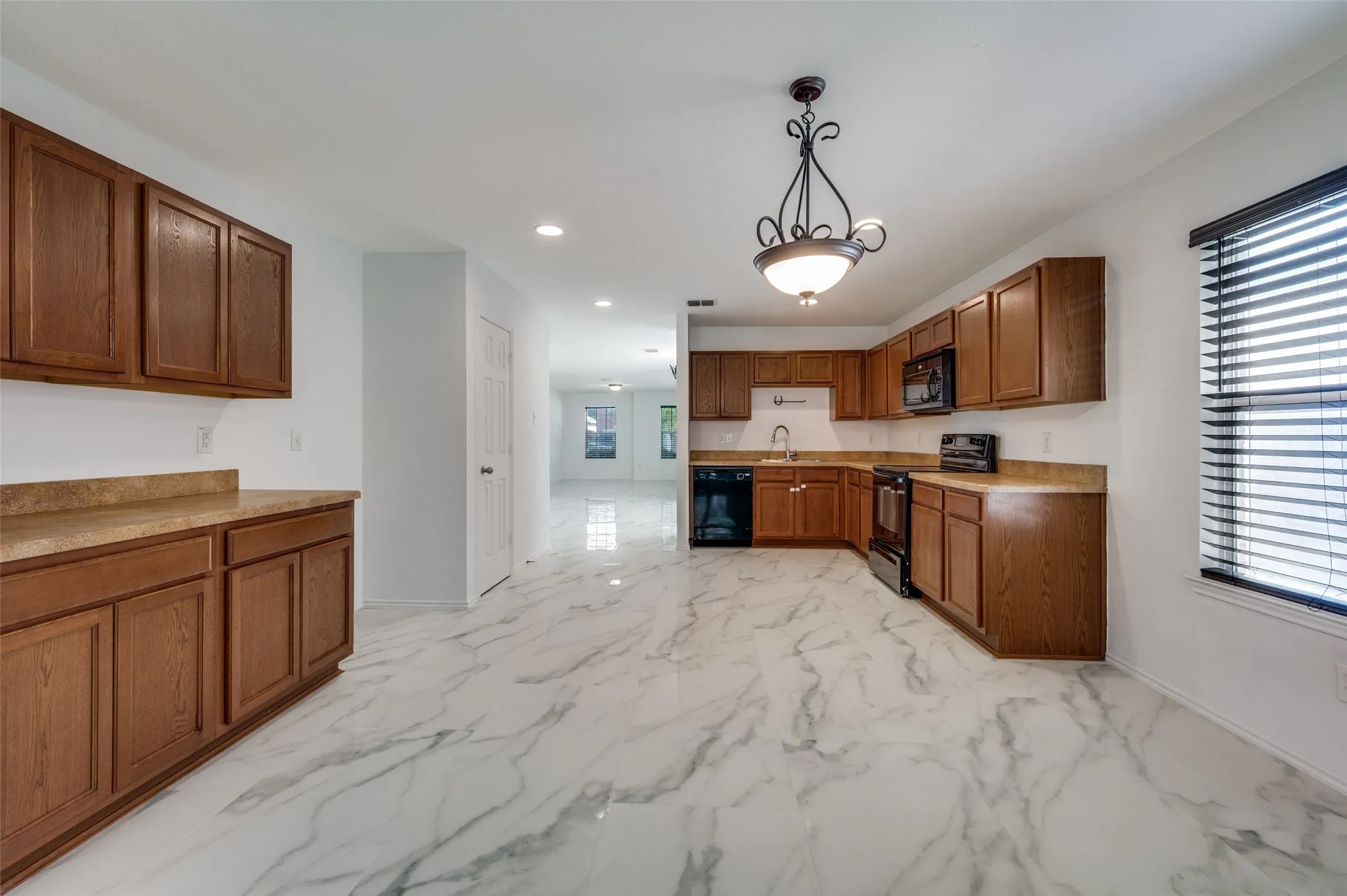 Kitchen featuring wood cabinetry, stone-finish countertops, black appliances, a window with blinds, and white marble-look flooring