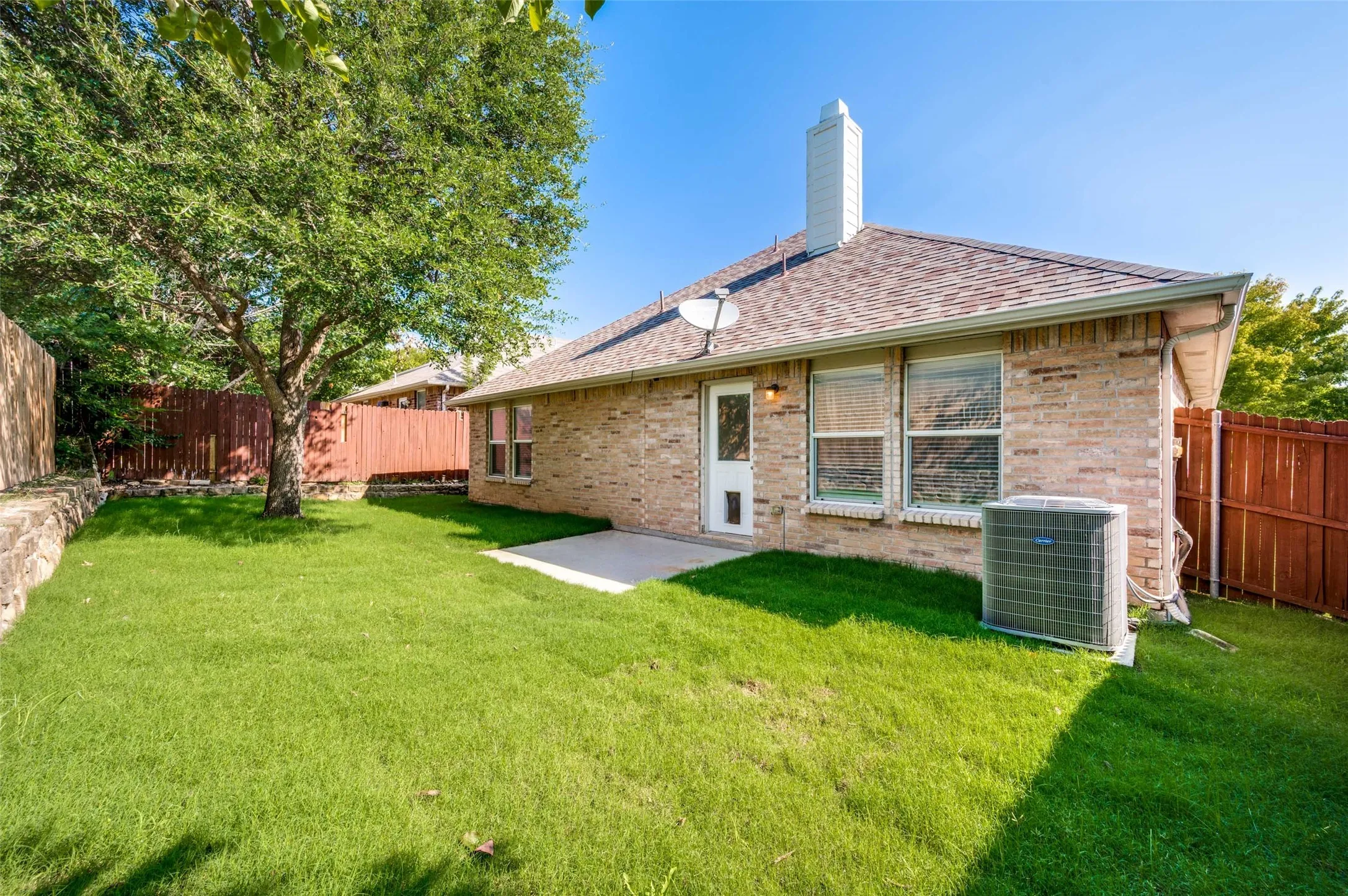Expansive backyard featuring a mature tree, manicured lawn, and privacy fencing