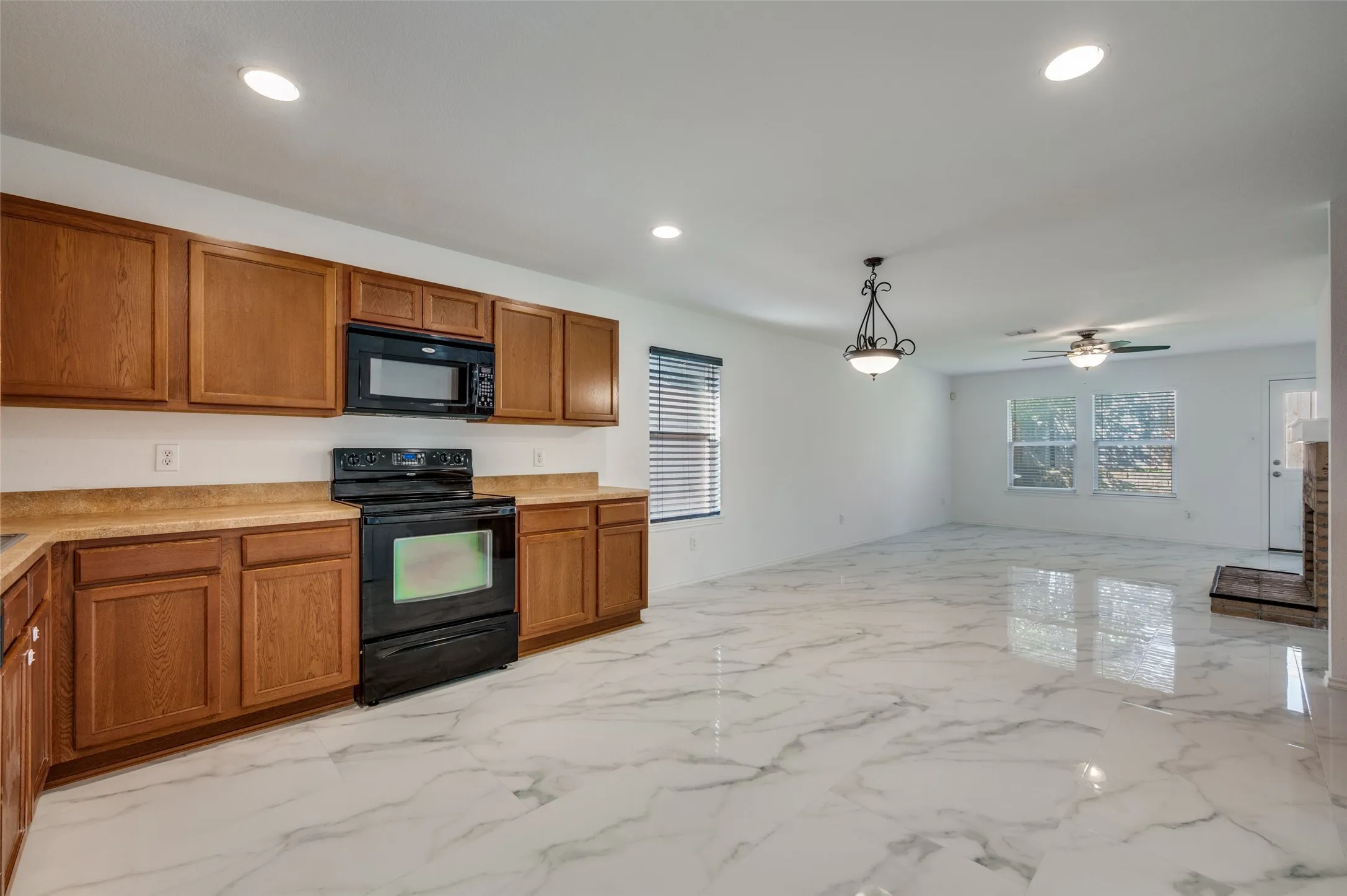 Contemporary kitchen featuring wood cabinetry, laminate countertops, and a black appliance suite with a microwave and range