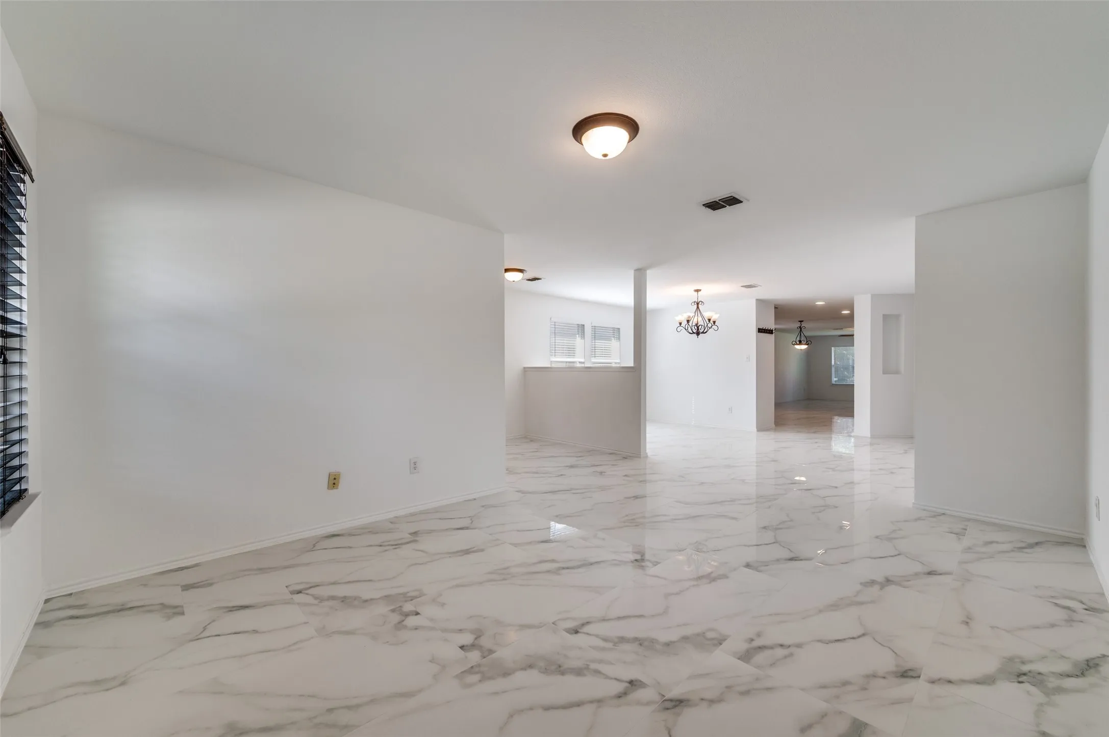 Spacious interior featuring marble-finish flooring throughout, a flush-mount ceiling light fixture, and horizontal window blinds