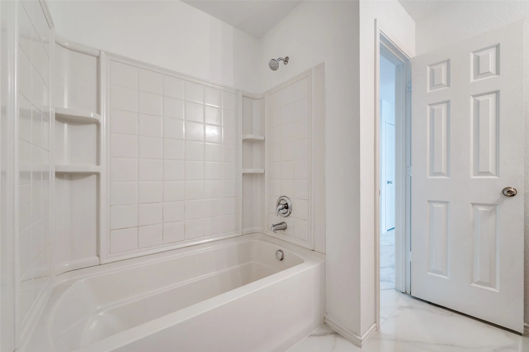 White tub and shower combination with integrated shelving