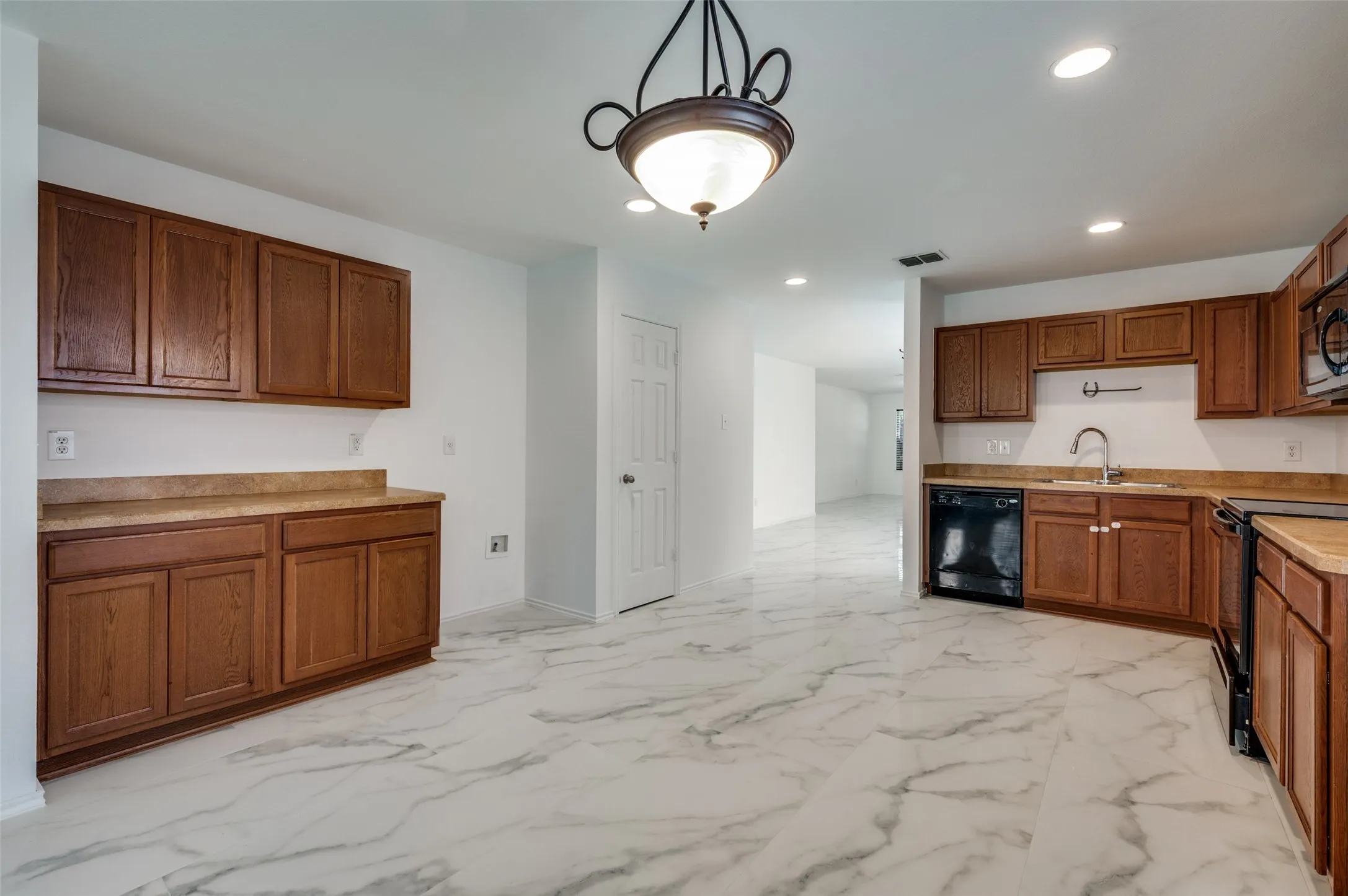 Spacious kitchen featuring sleek tile flooring, rich wood-finish cabinetry, and a black appliance suite