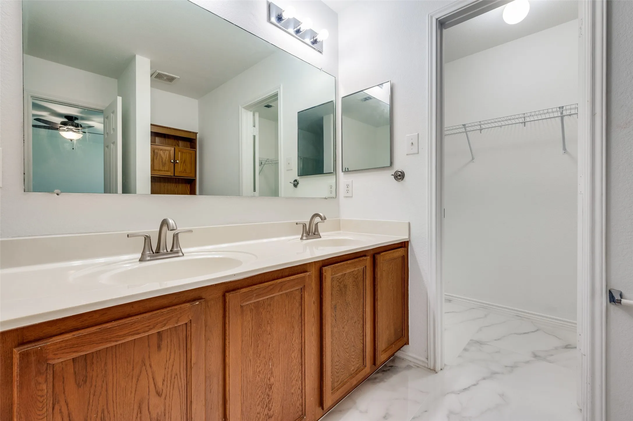 Bathroom vanity featuring a dual sink, wood-finish cabinetry, and a spacious counter
