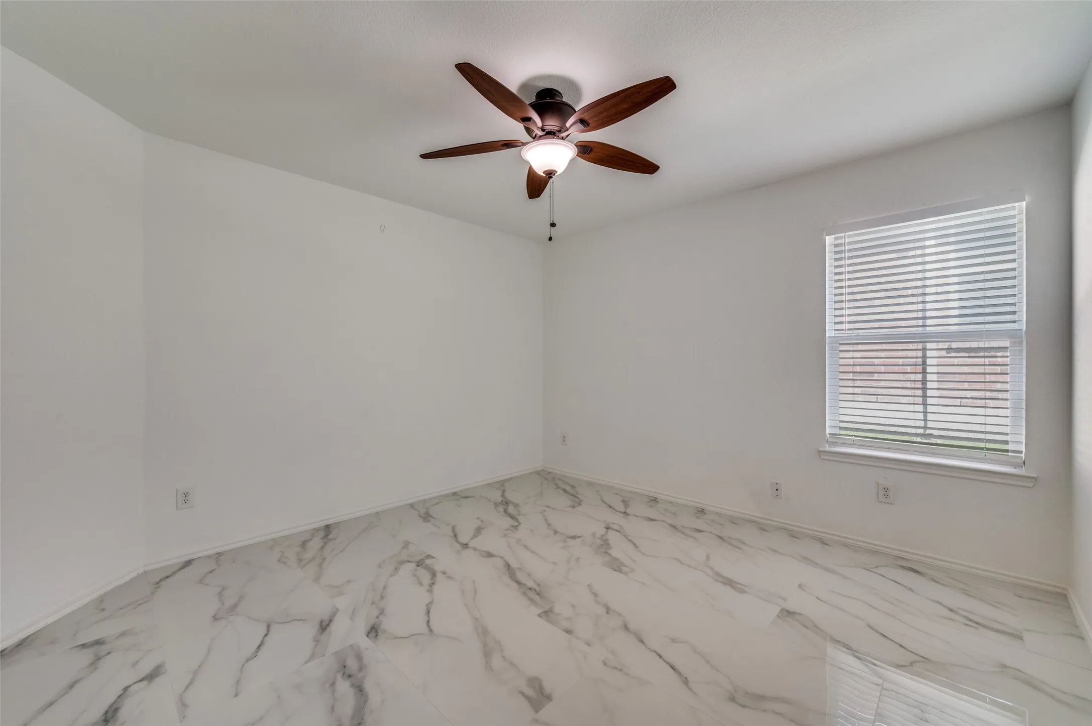 Room featuring white walls, marble-patterned tile flooring, and a ceiling fan with integrated lighting