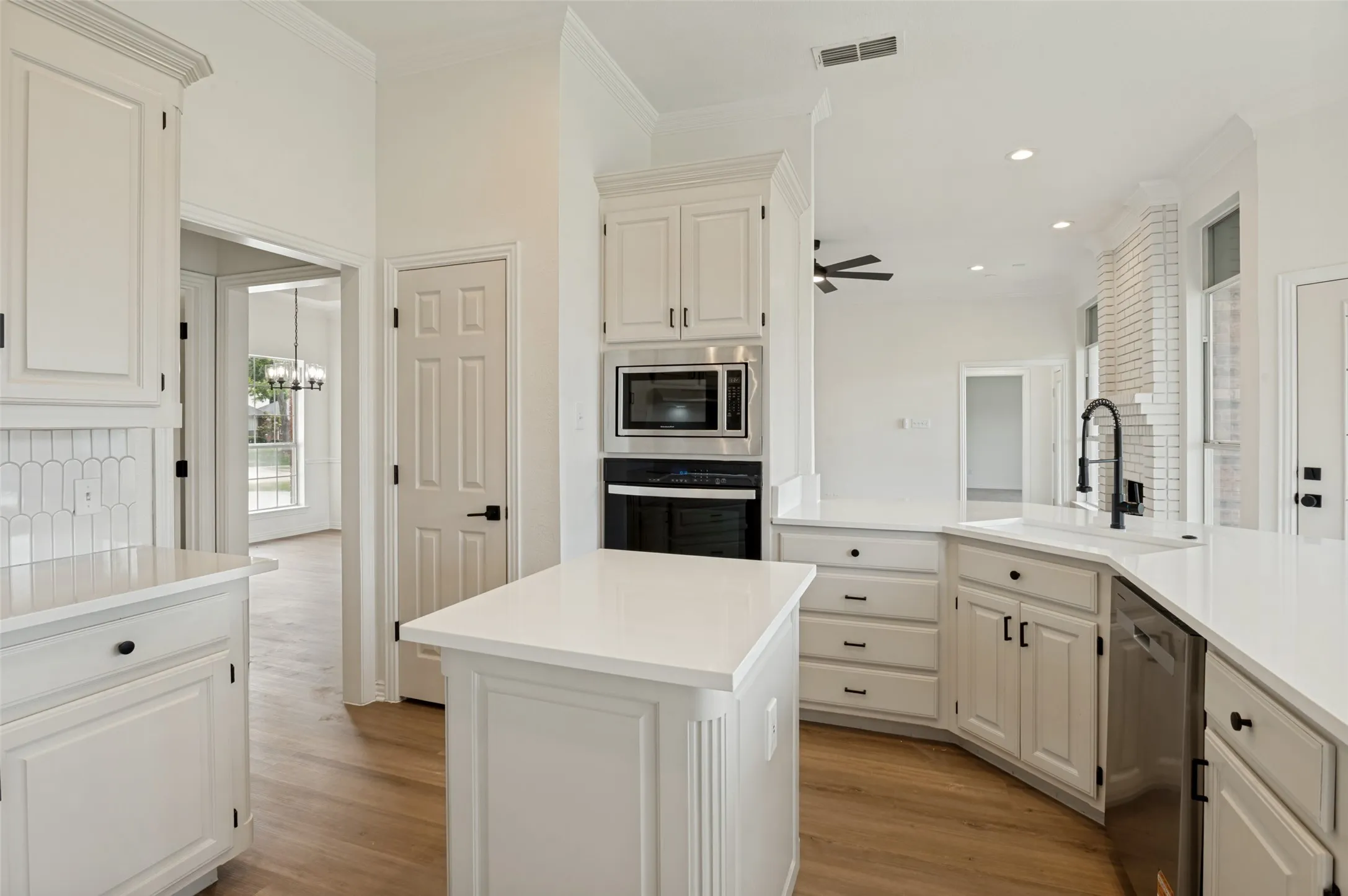Contemporary kitchen featuring white cabinetry, light-toned countertops, integrated stainless steel appliances, a center island, and wood-finish flooring