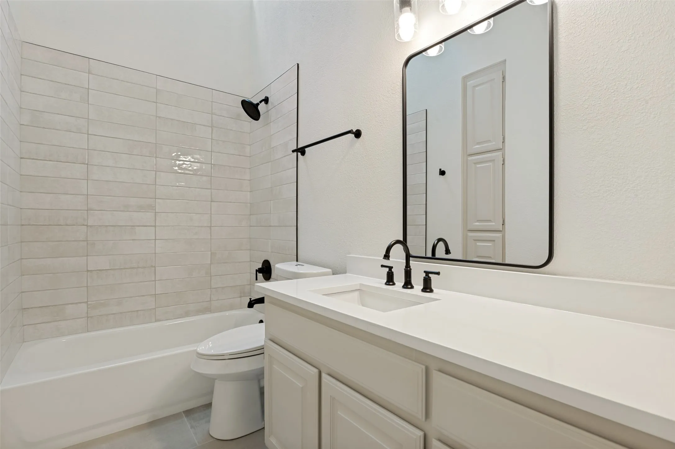 Bathroom featuring a single vanity with a white countertop, undermount sink, and matte black faucet