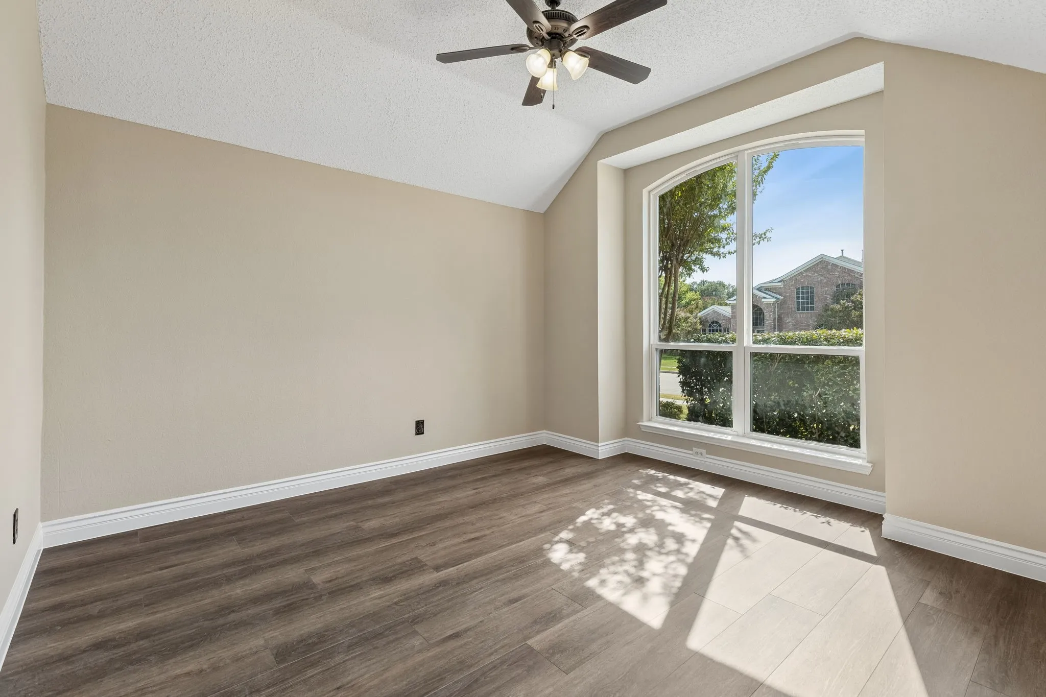 The formal dining or living space with vaulted ceiling offers ceiling fan, fresh paint, and new LVP flooring.