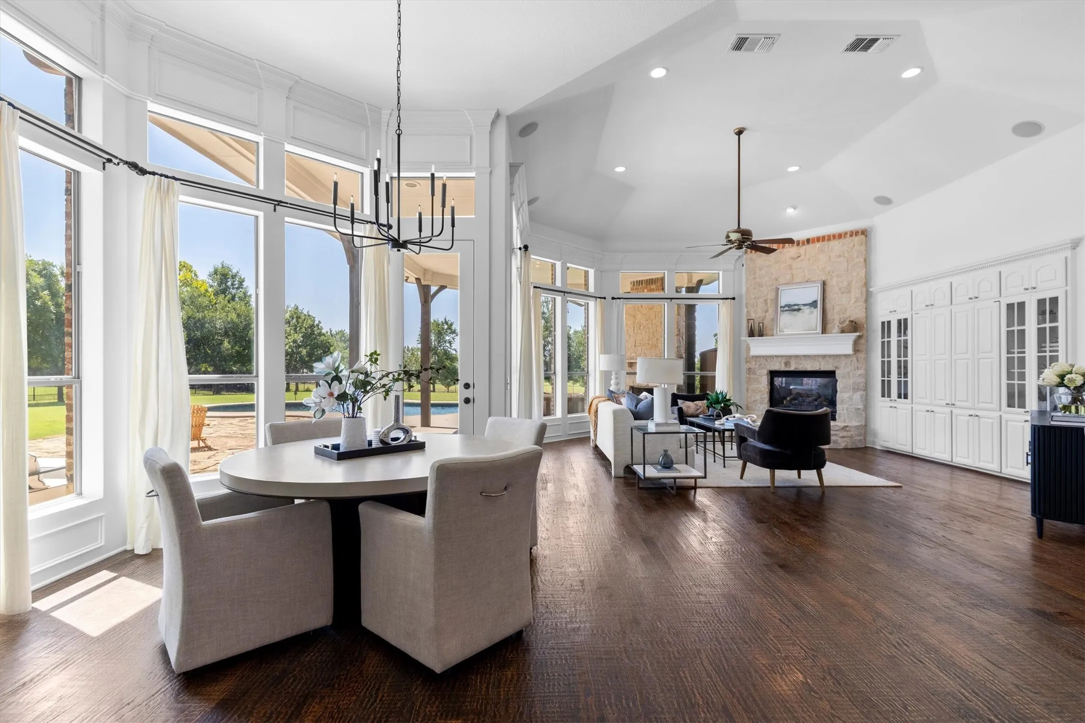 Expansive living area featuring wood-finish flooring, a stone-clad fireplace with a mantle, and built-in cabinetry
