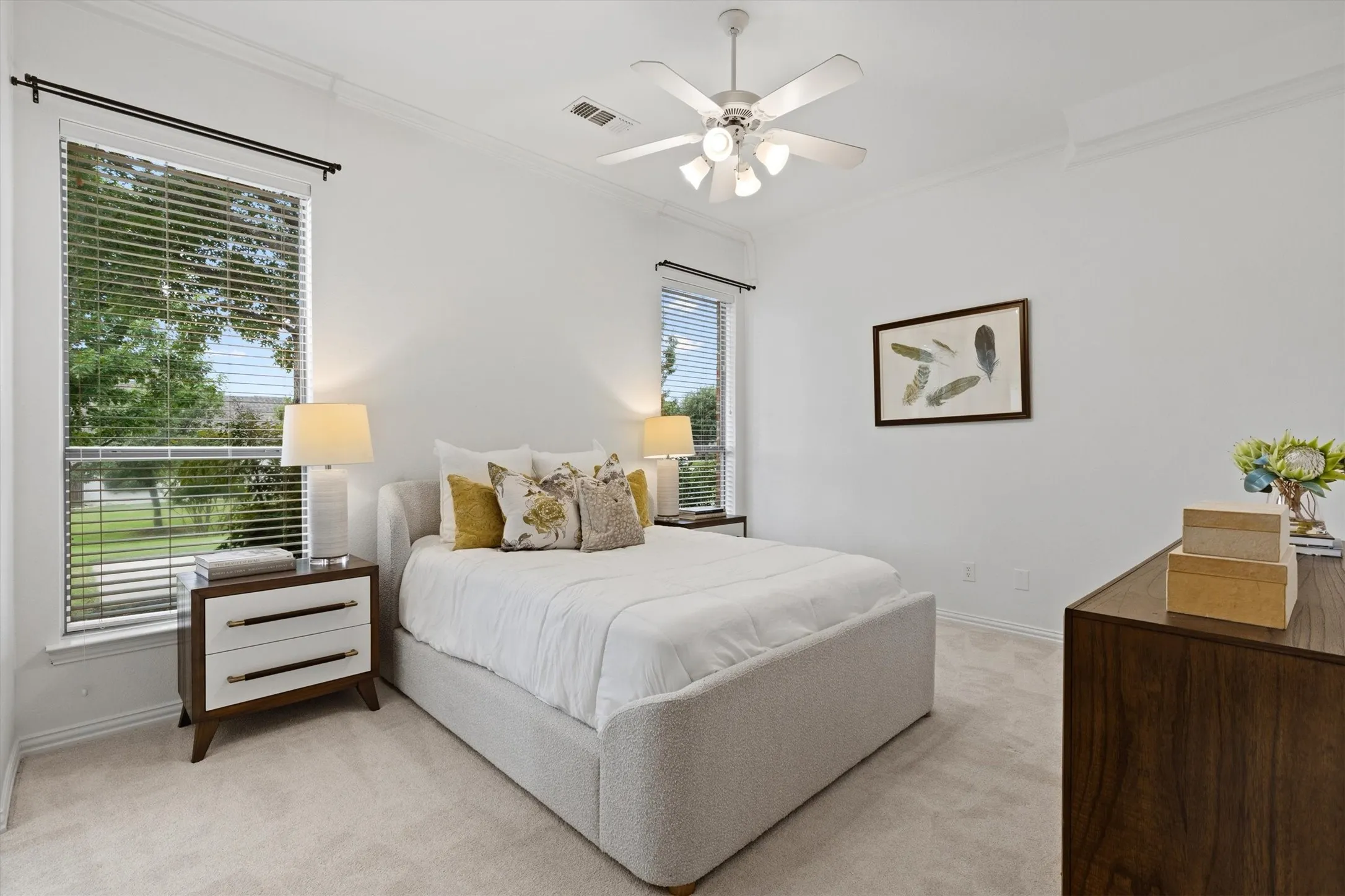 Carpeted room featuring a ceiling fan with integrated lighting, crown molding, and two windows with blinds