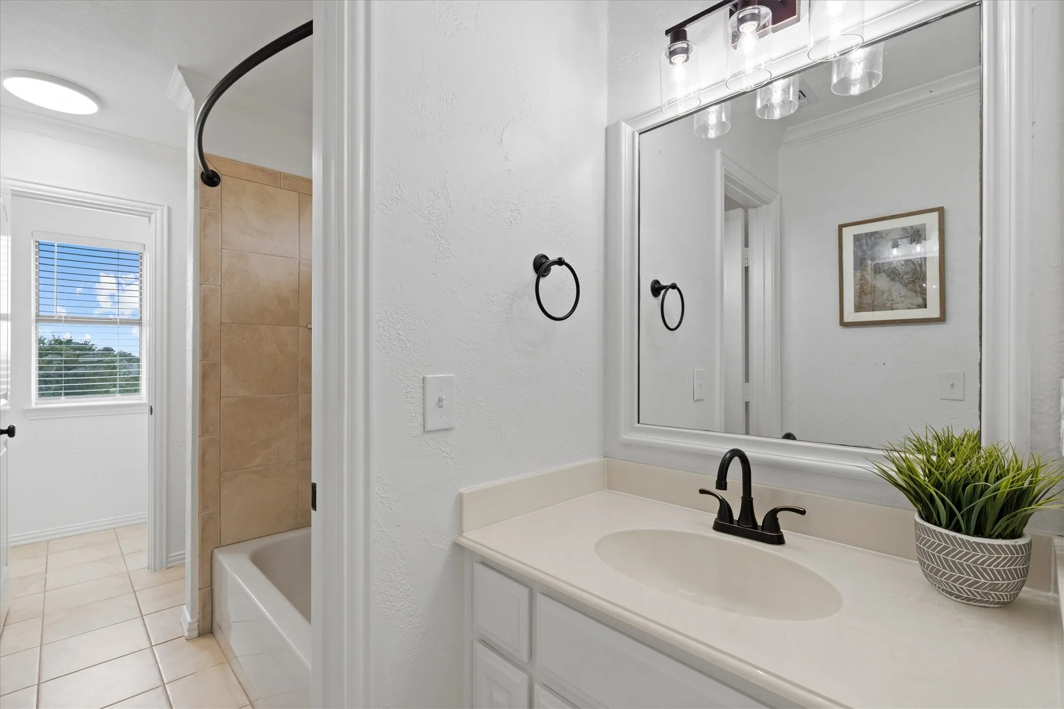 Bathroom vanity with an integrated sink, black faucet, and framed mirror