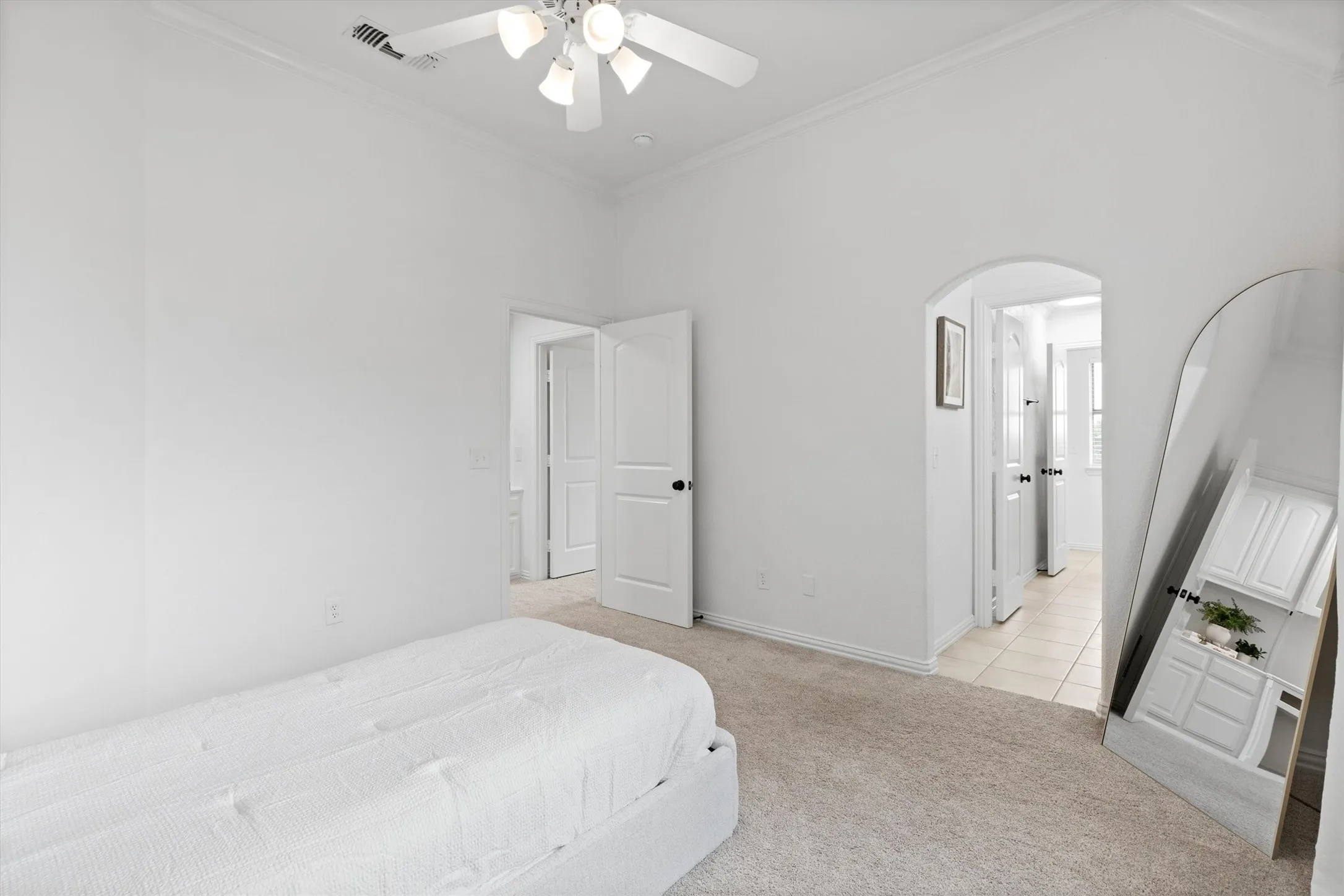 Carpeted interior room with white walls and a white ceiling fan with integrated lighting