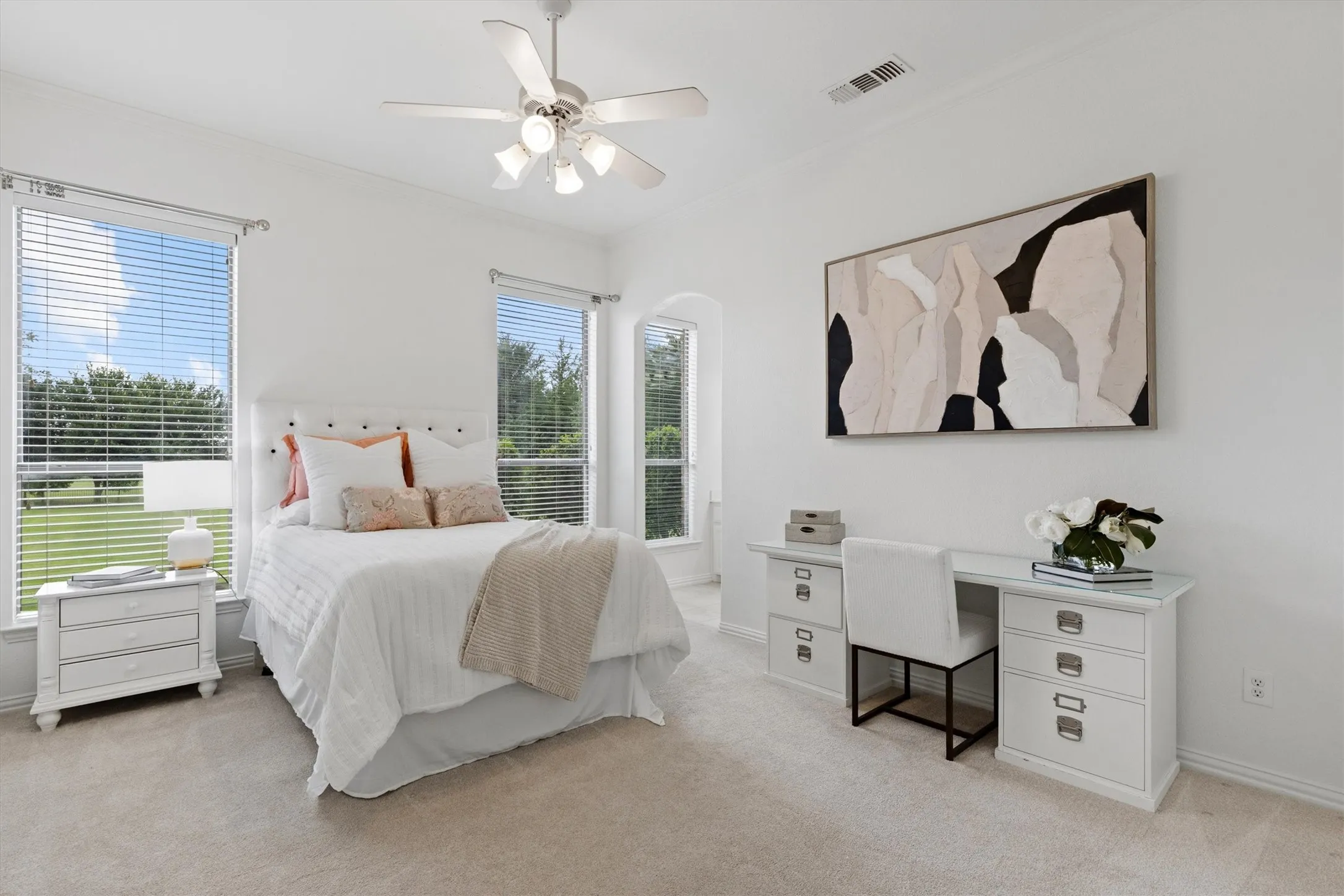 Carpeted room featuring multiple windows with horizontal blinds, a white ceiling fan with light fixture, and an arched architectural detail