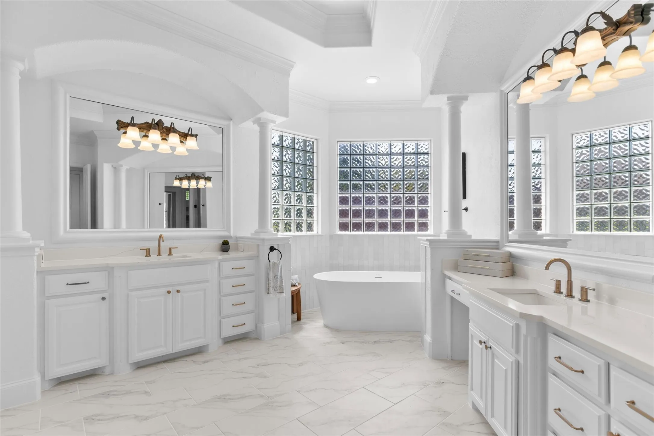 Spacious bathroom featuring dual vanities with white cabinetry and light-toned countertops
