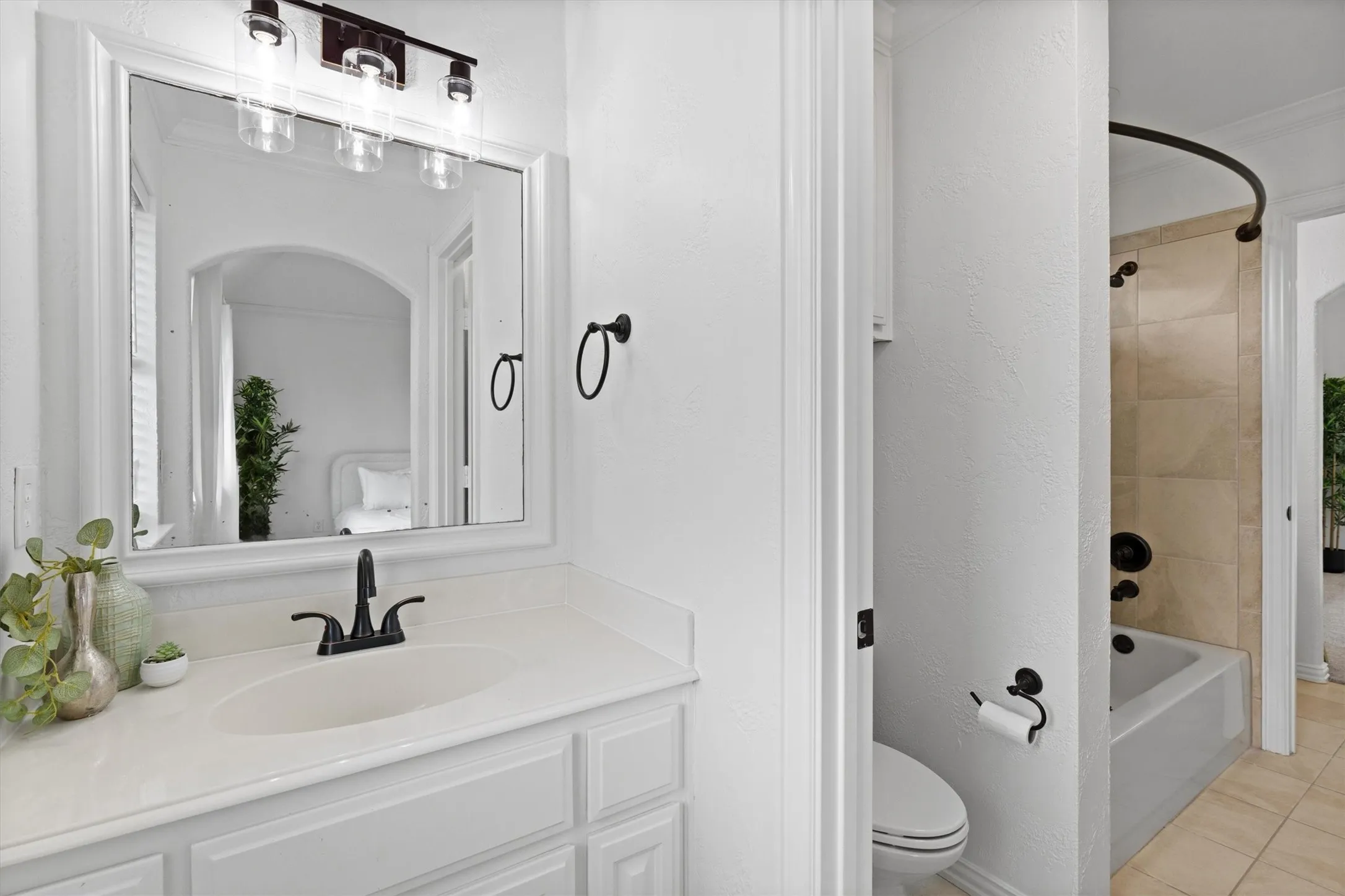 Bathroom vanity with white cabinetry, integrated sink, and dark bronze faucet
