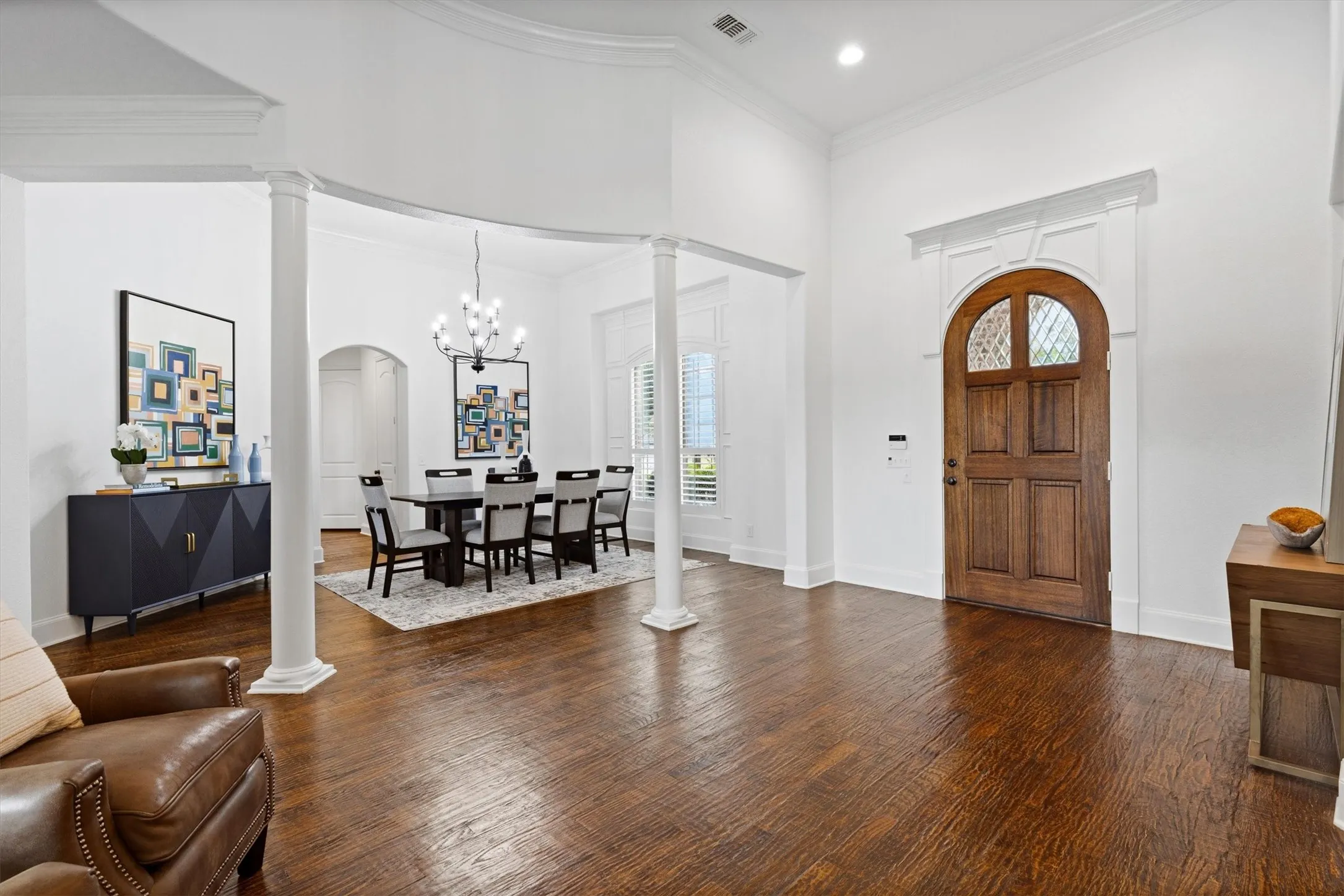 Grand entry foyer featuring an arched wooden front door with decorative glass, high ceilings, and rich wood-finish flooring