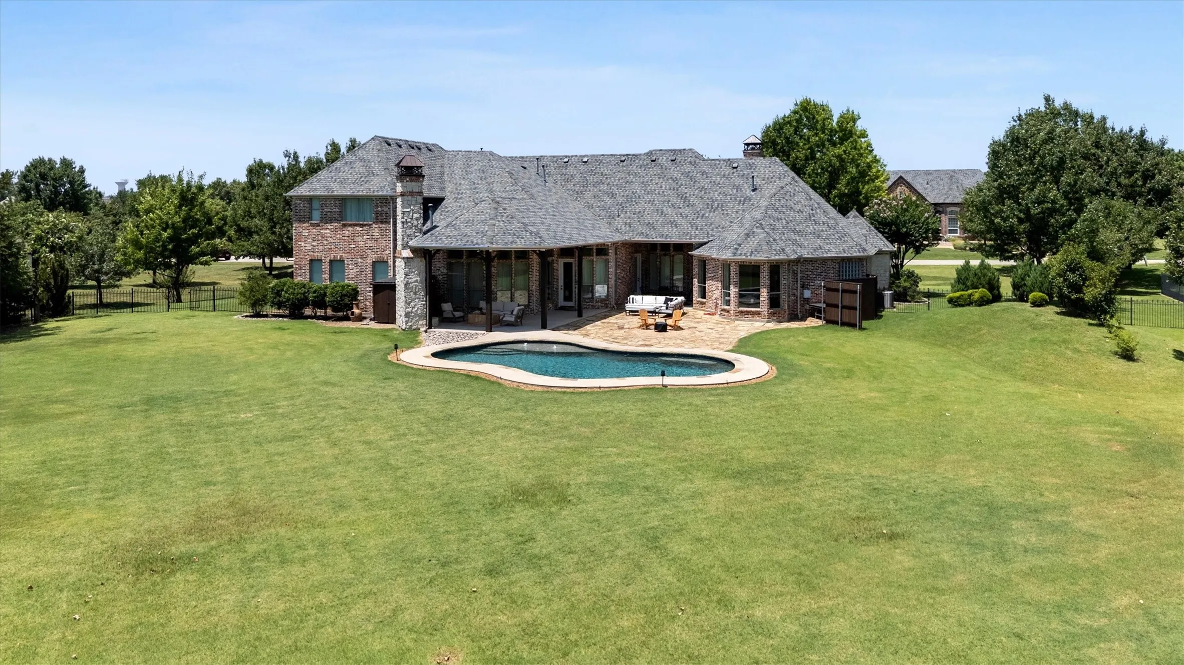 Expansive rear exterior featuring a freeform swimming pool with a stone coping