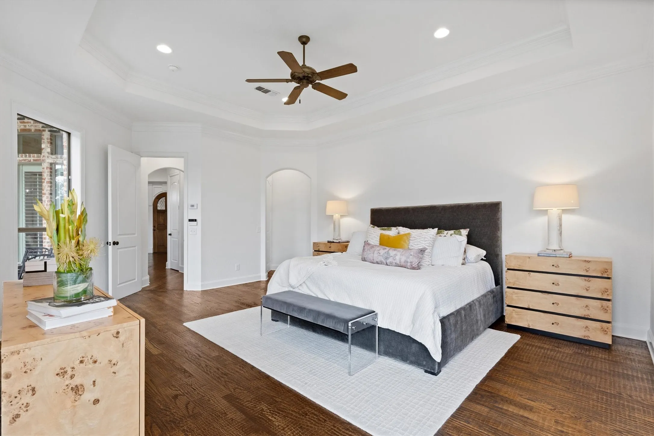 Spacious room featuring wood-finish flooring, a tray ceiling, and a ceiling fan with integrated lighting