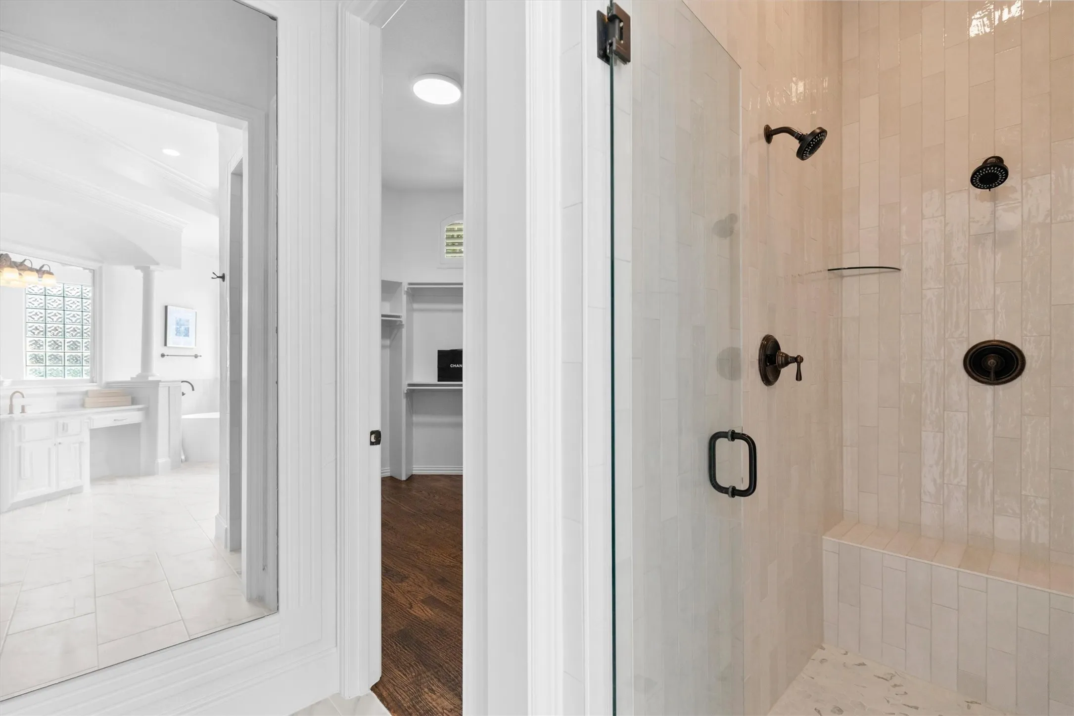 Glass-enclosed shower with subway tile surround, integrated bench, and dark bronze fixtures