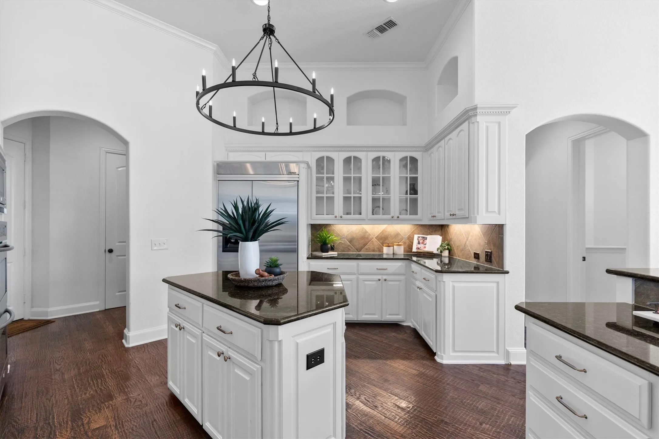Kitchen featuring white cabinetry, dark stone countertops, stainless steel appliances, a center island, and wood-finish flooring