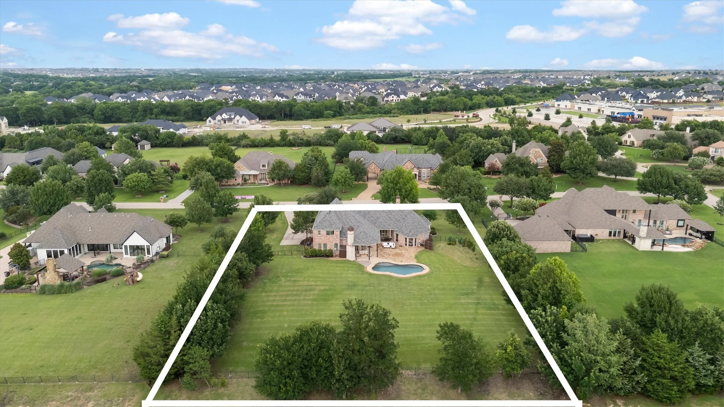 Aerial perspective showcasing a multi-story home with a light-colored brick exterior, a dark shingle roof, and multiple windows