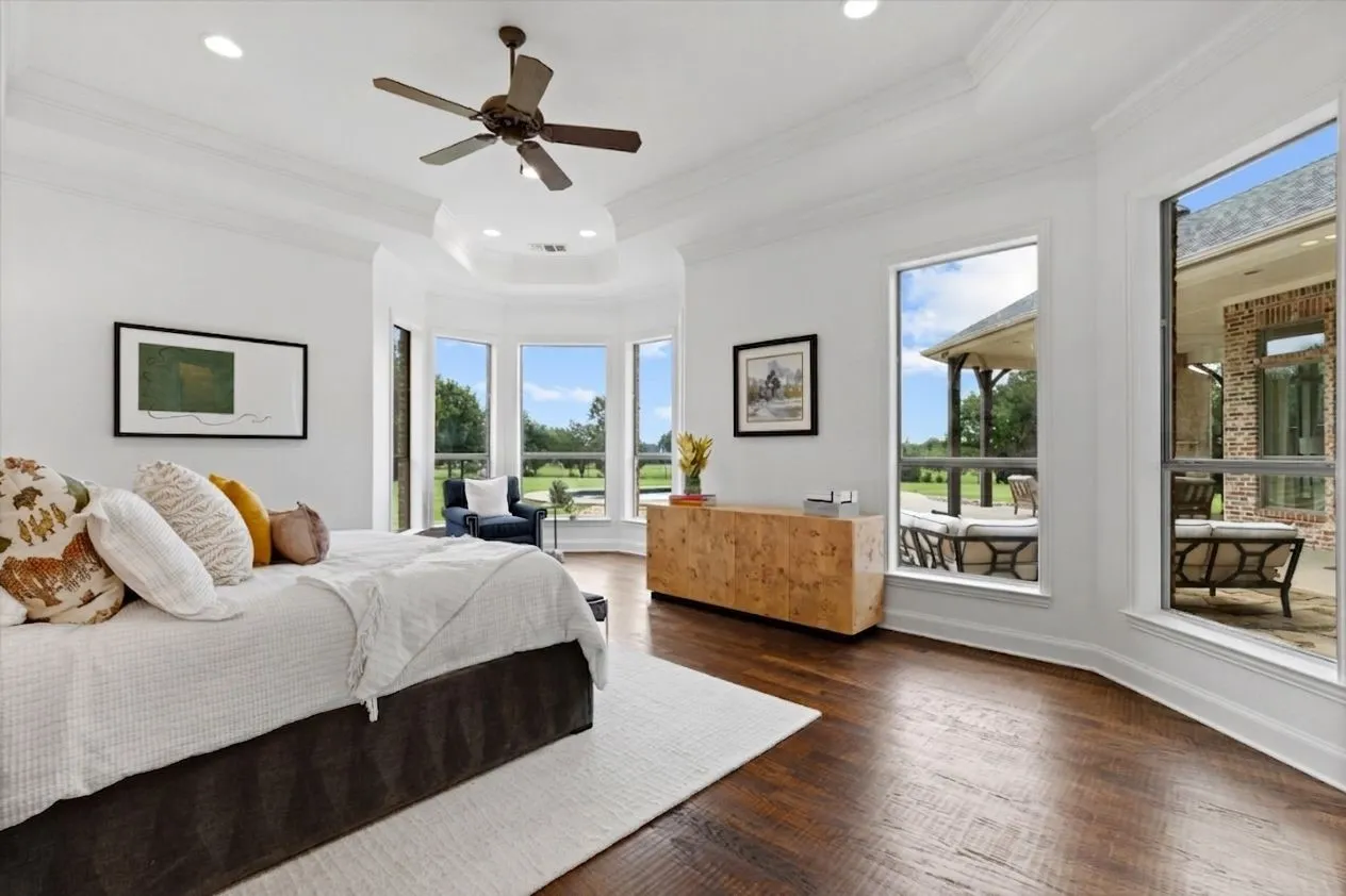 Spacious room featuring rich wood-finish flooring, a tray ceiling with recessed lighting, and a ceiling fan