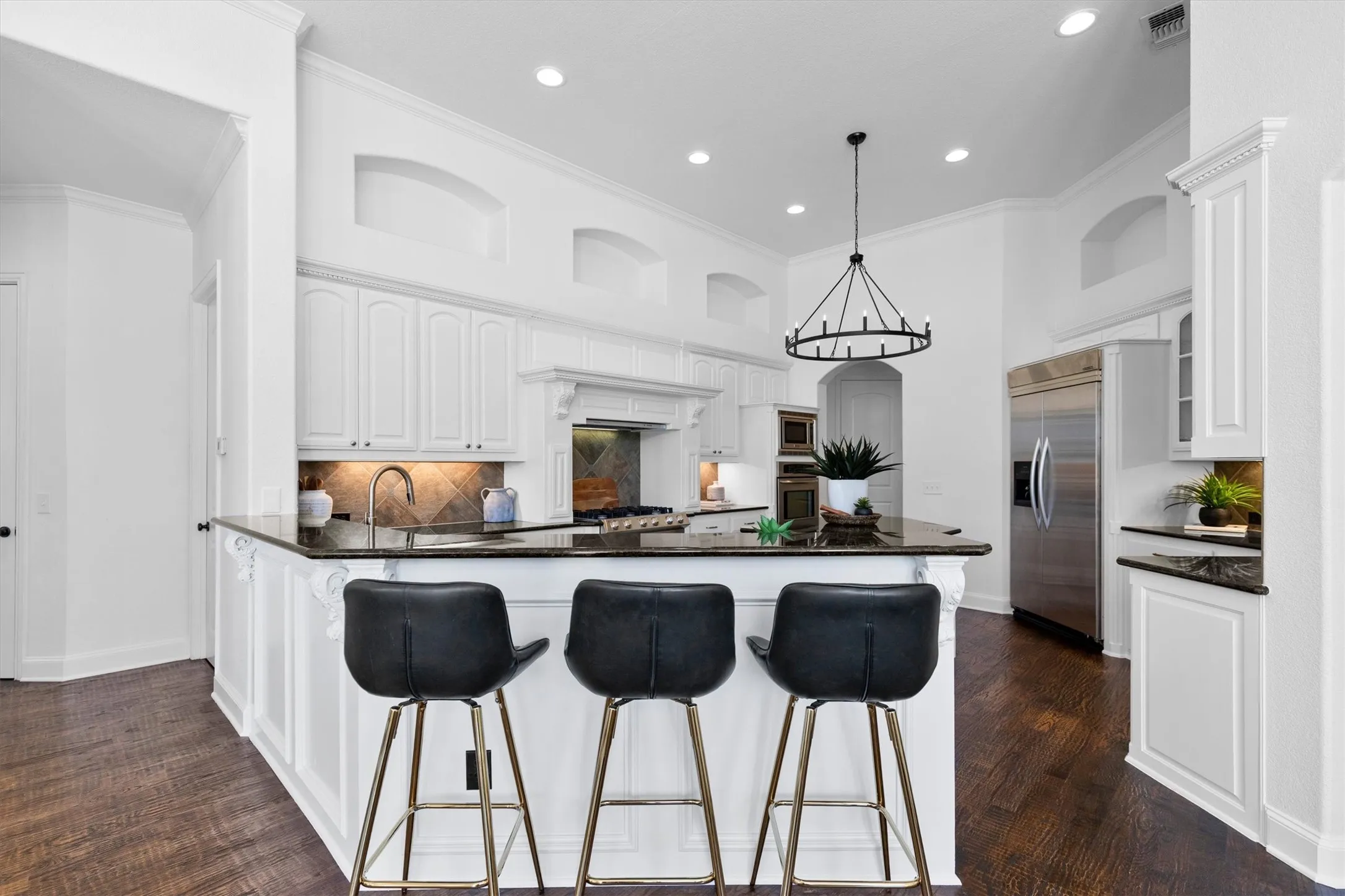 Gourmet kitchen with dark wood-finish flooring, white cabinetry, dark countertops, a stainless steel refrigerator, and recessed lighting