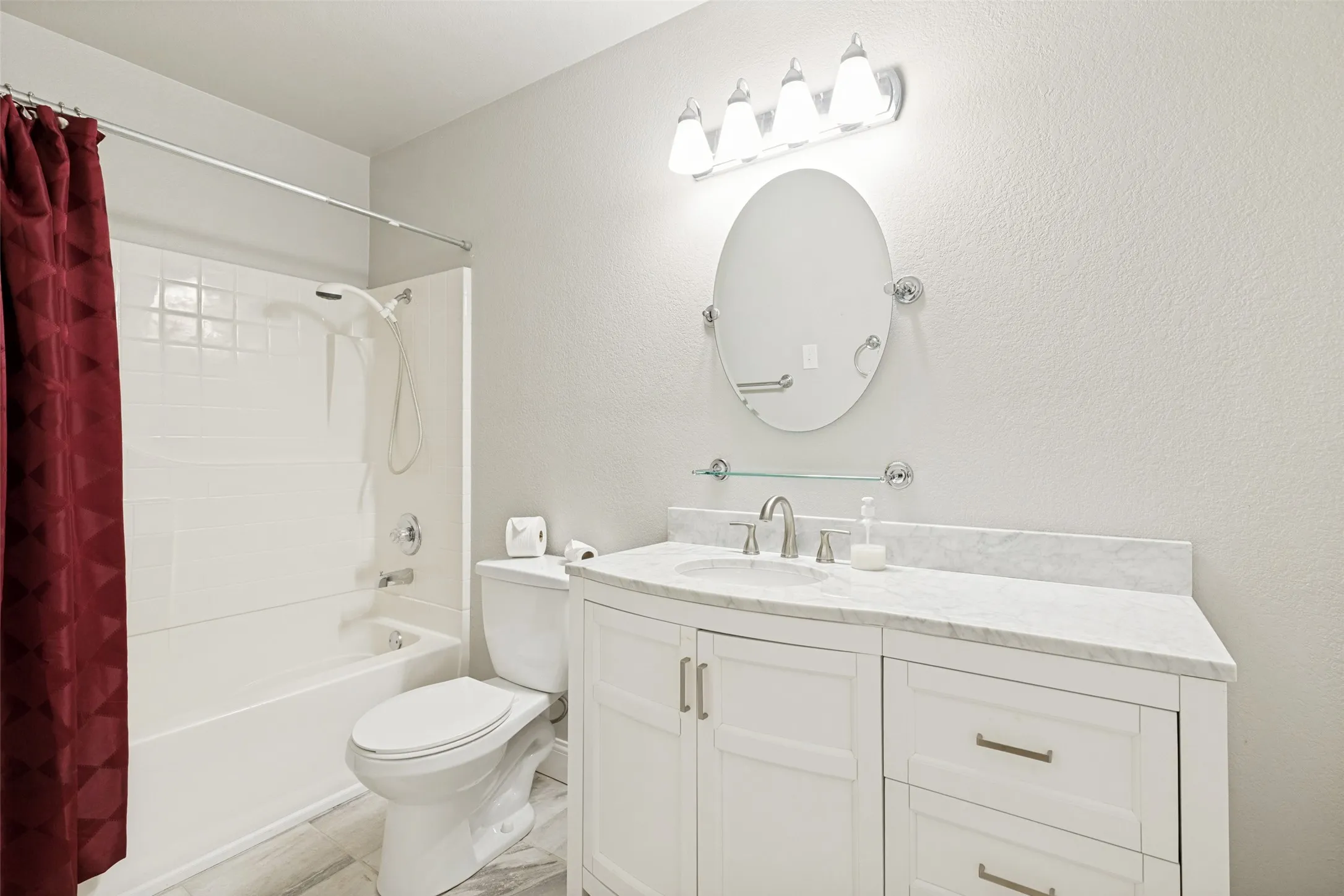 Bathroom featuring a white vanity with a stone countertop, an oval mirror, and a chrome light fixture