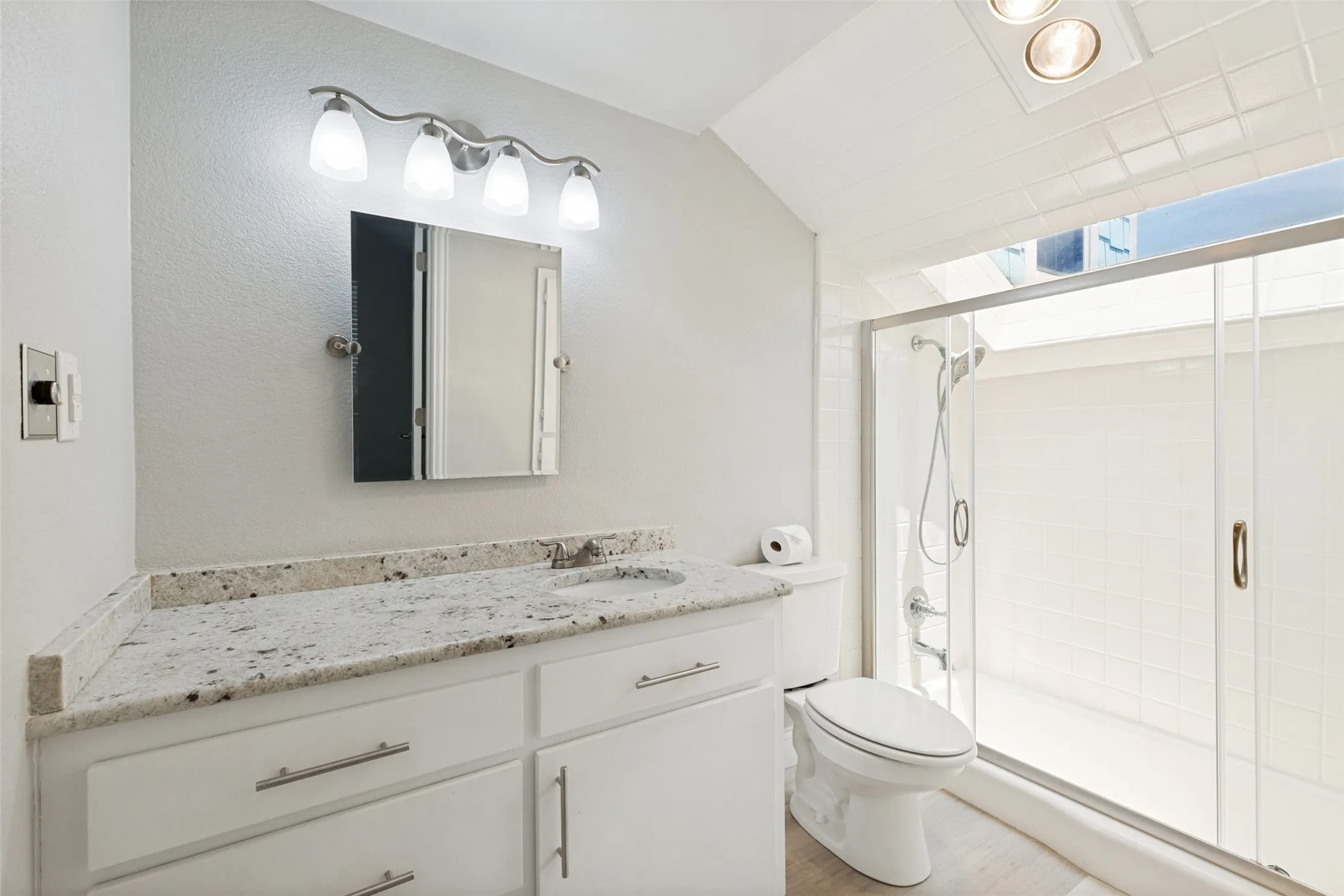 Bathroom featuring a spacious walk-in shower with a glass enclosure, white tile surround, and a skylight