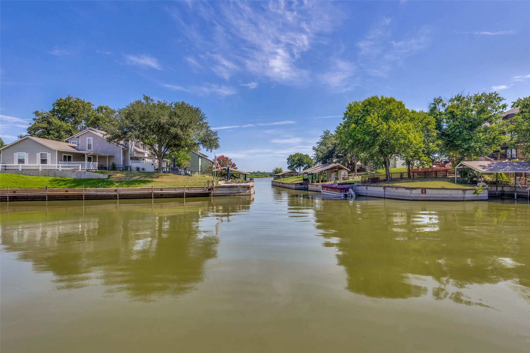 Waterfront property with private boat slips, mature trees, and covered patios