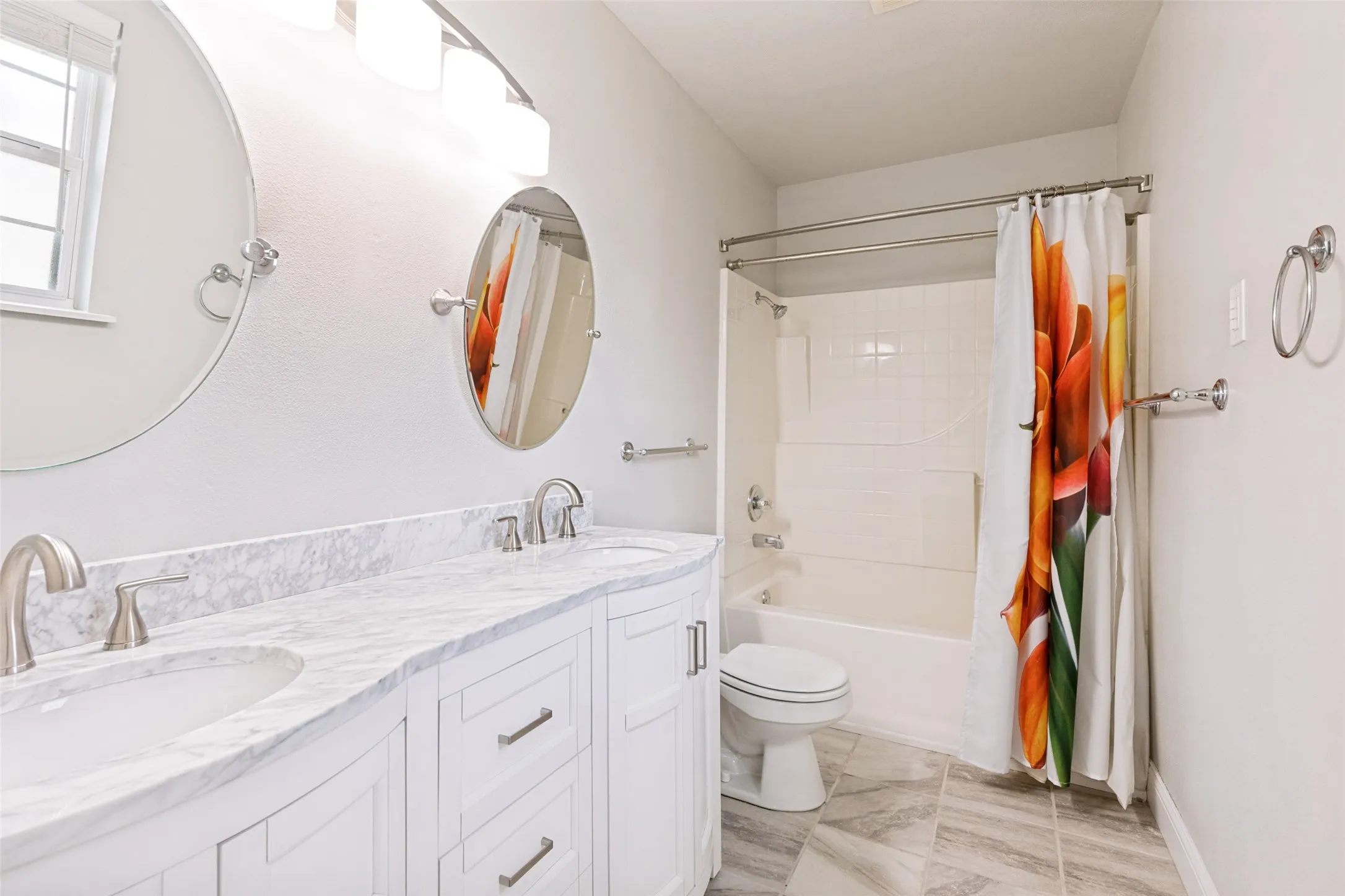 Double vanity with white cabinetry and marble-patterned countertops