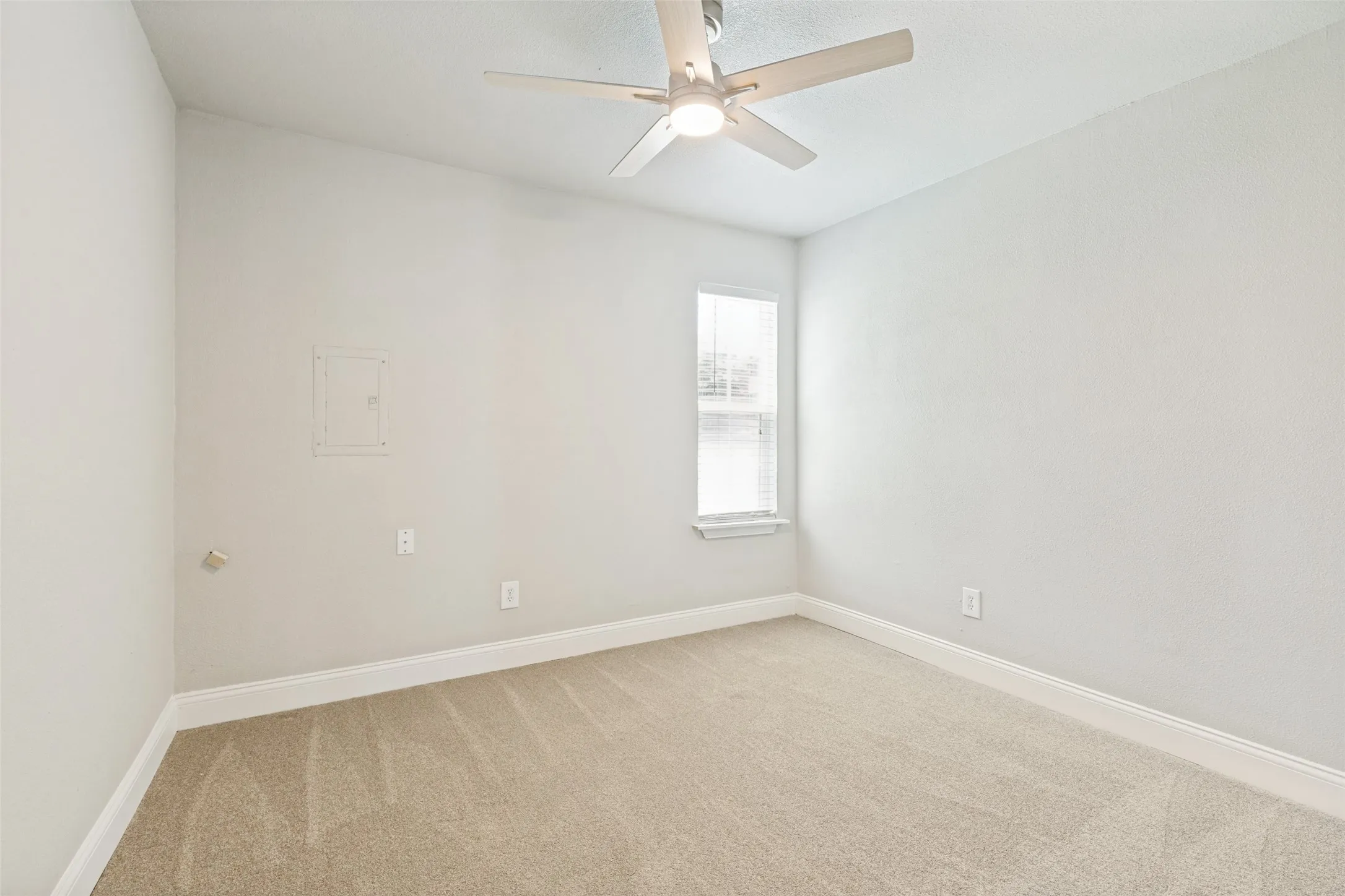 Carpeted room featuring a ceiling fan with integrated lighting, a single window with blinds, and white baseboards