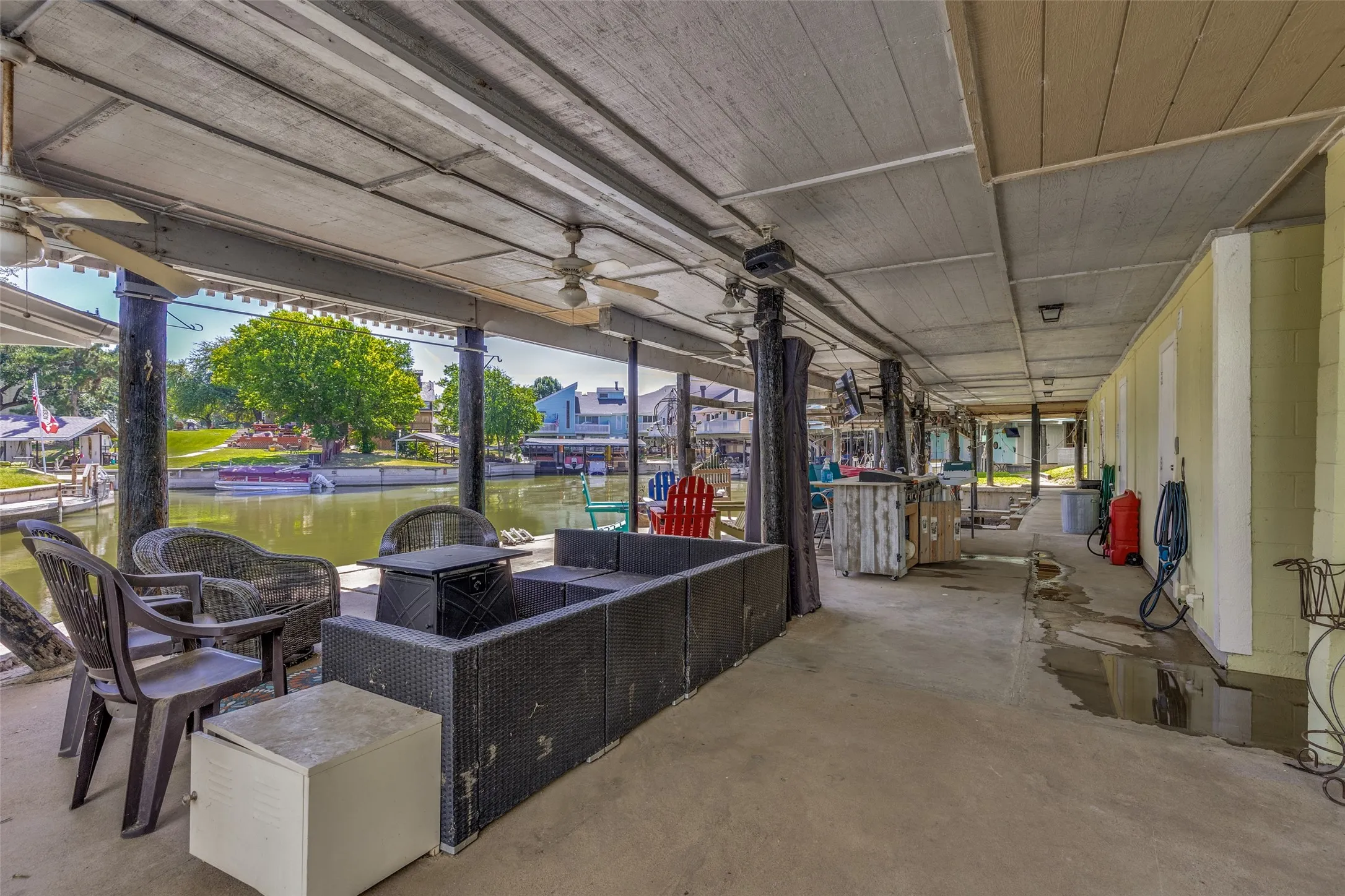 Expansive covered patio featuring concrete flooring, exposed wood ceiling, and ceiling fans