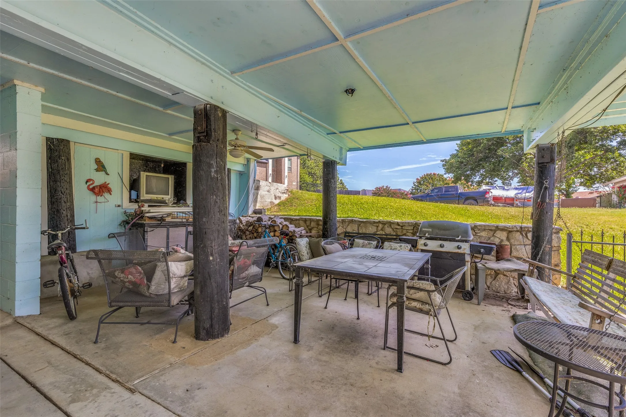 Covered patio featuring a concrete slab, stone perimeter wall, and wood support beams