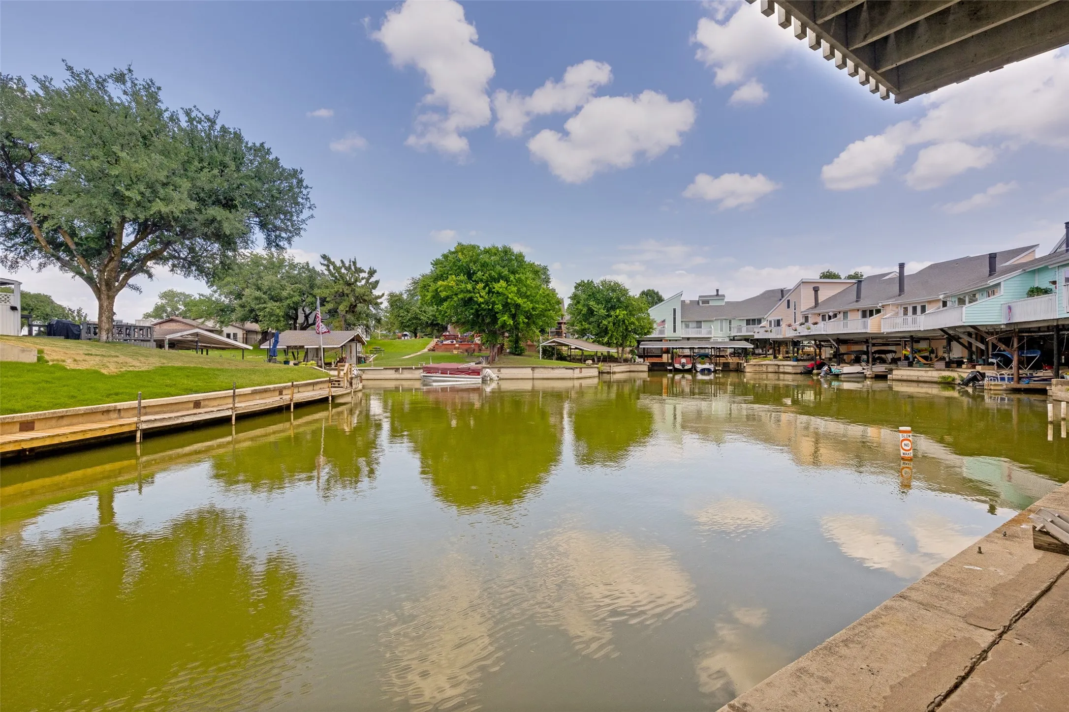 Waterfront property featuring an expansive water body, a concrete retaining wall, and multiple dock structures