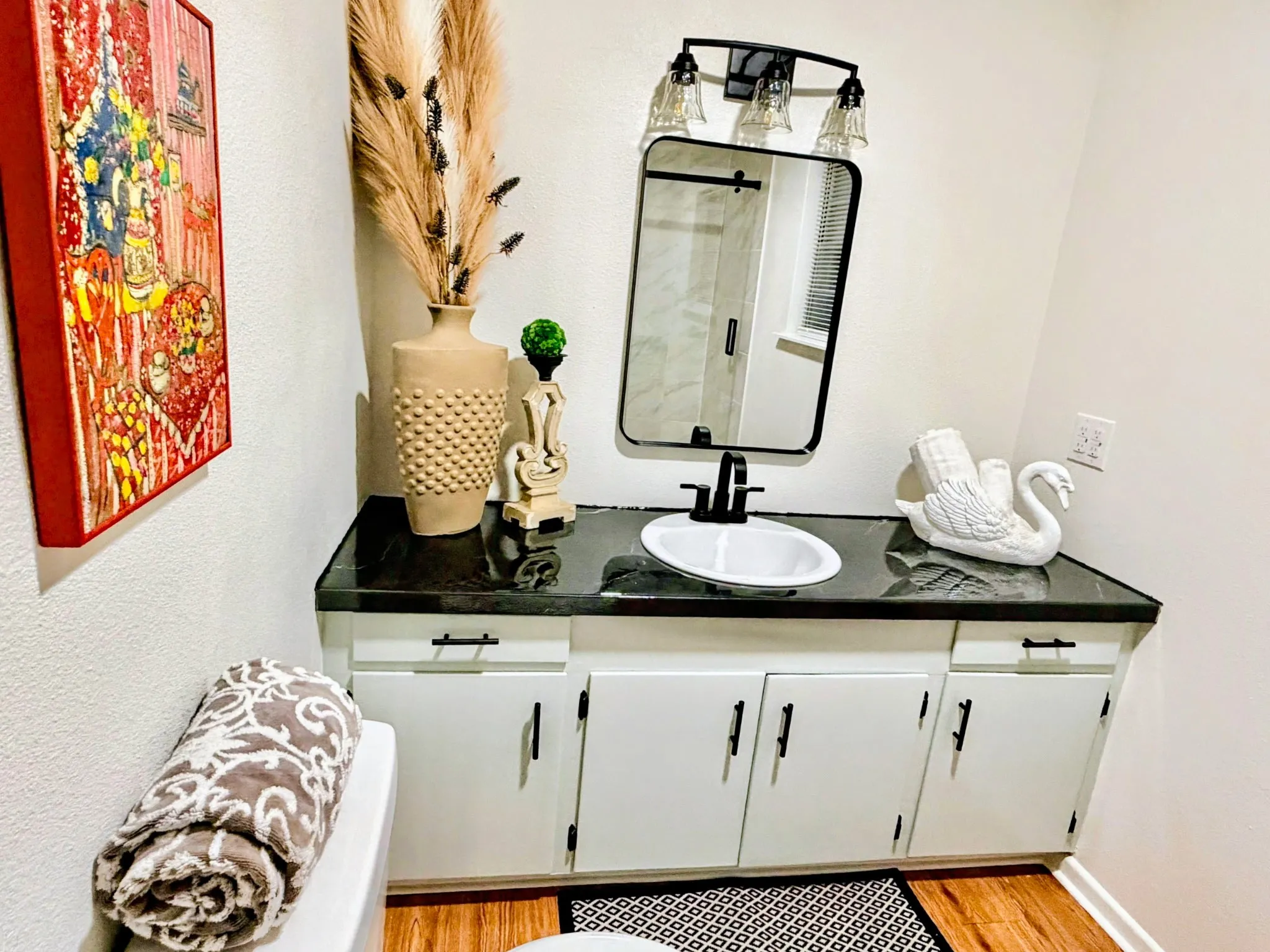 Vanity with a black countertop, oval undermount sink, and black faucet