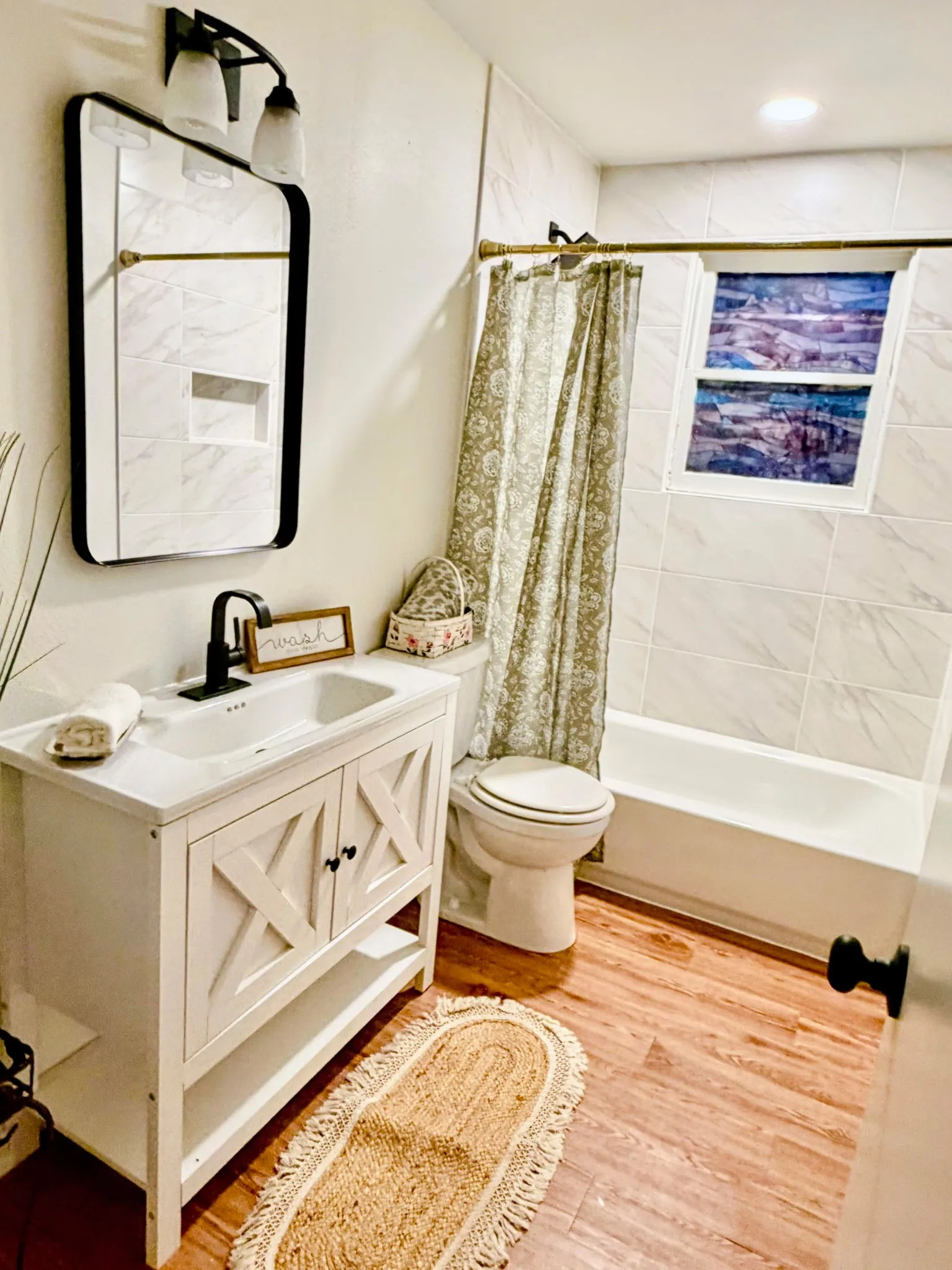 White vanity with cross-brace detailing, black hardware, and an integrated sink
