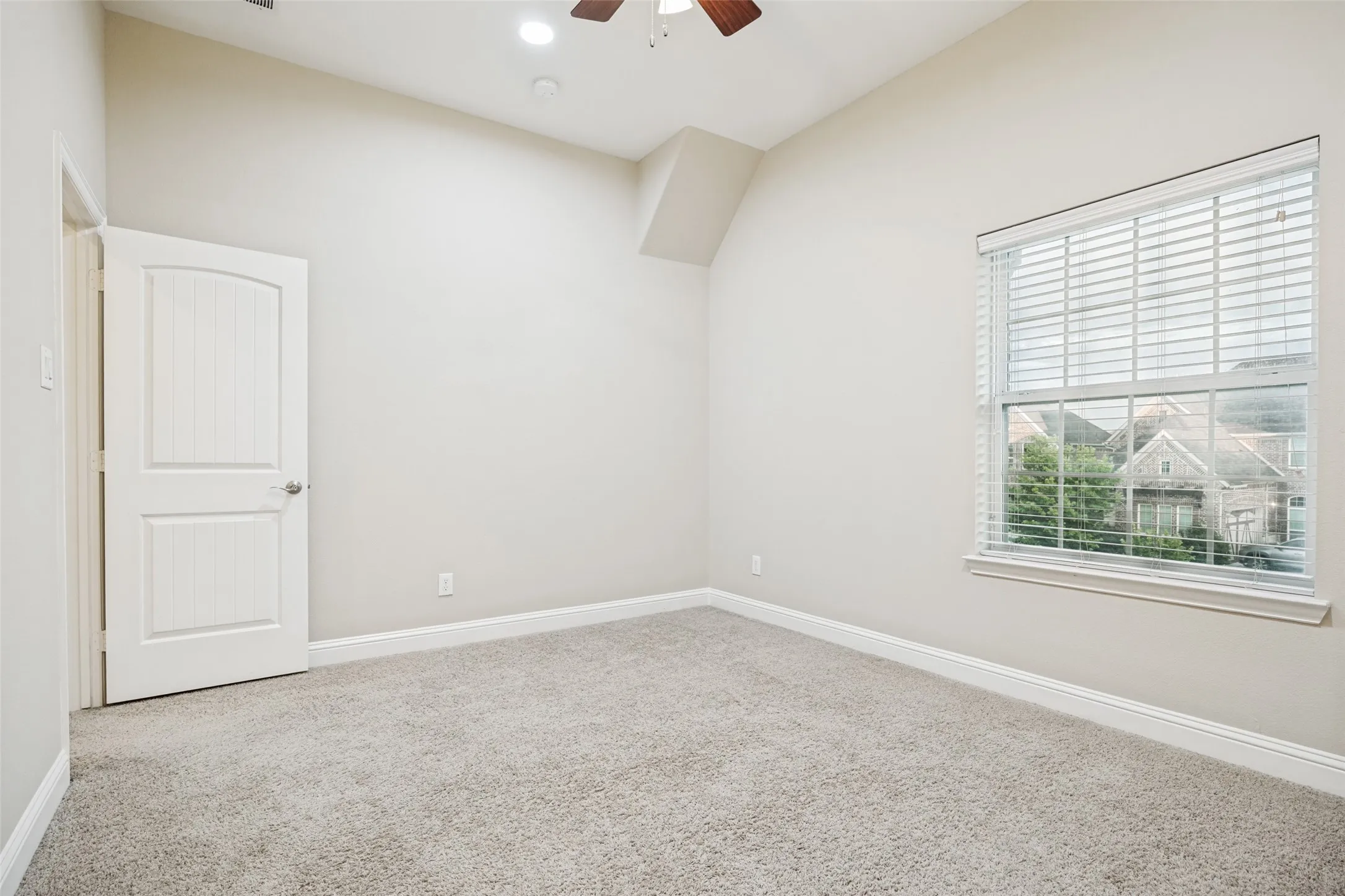 Carpeted room with vaulted ceiling and a ceiling fan