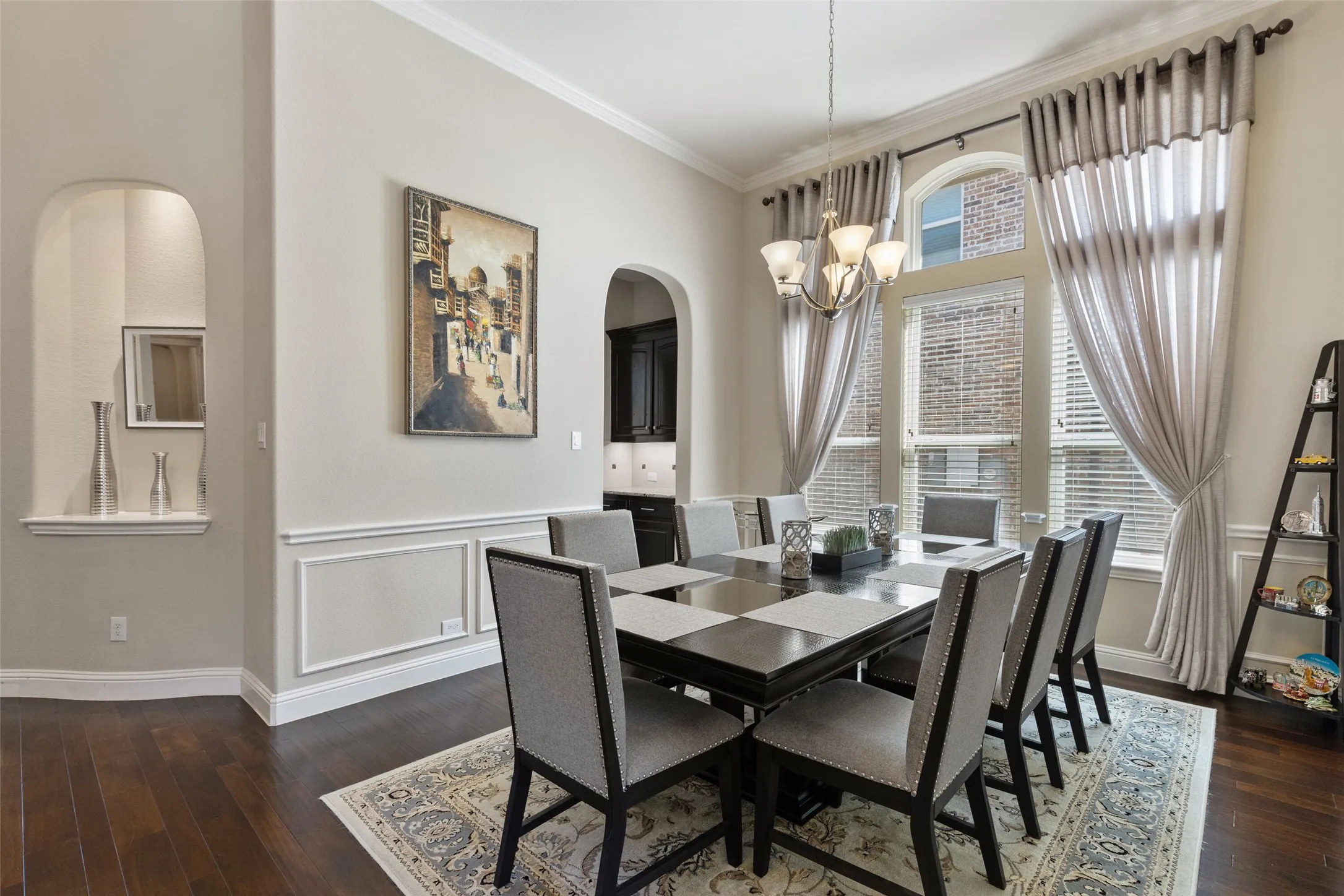 Formal dining area featuring wood-finish flooring, an arched display niche, crown molding, and wainscoting
