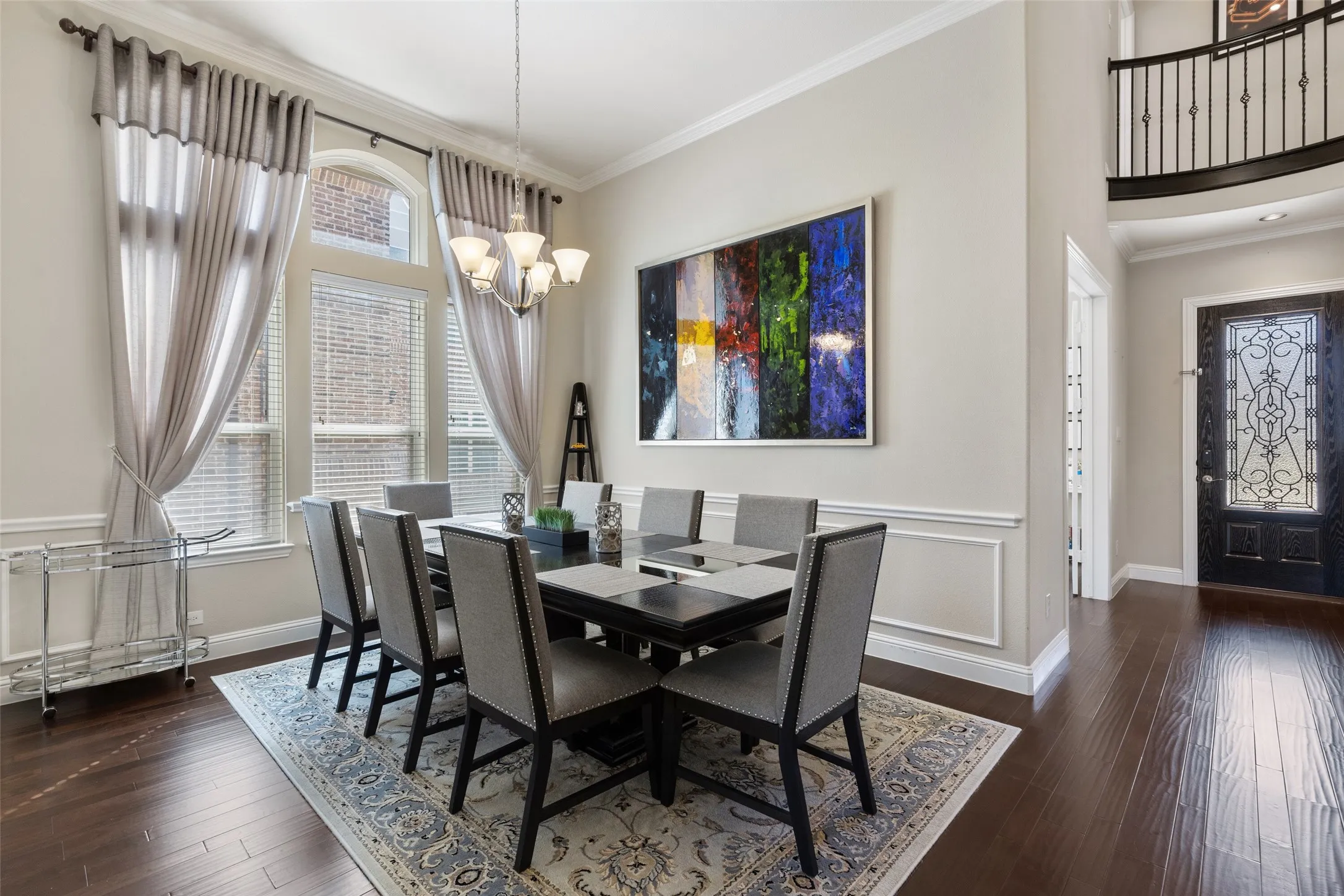 Formal dining area featuring rich wood-finish flooring, tall windows with transom detailing, and a multi-arm chandelier
