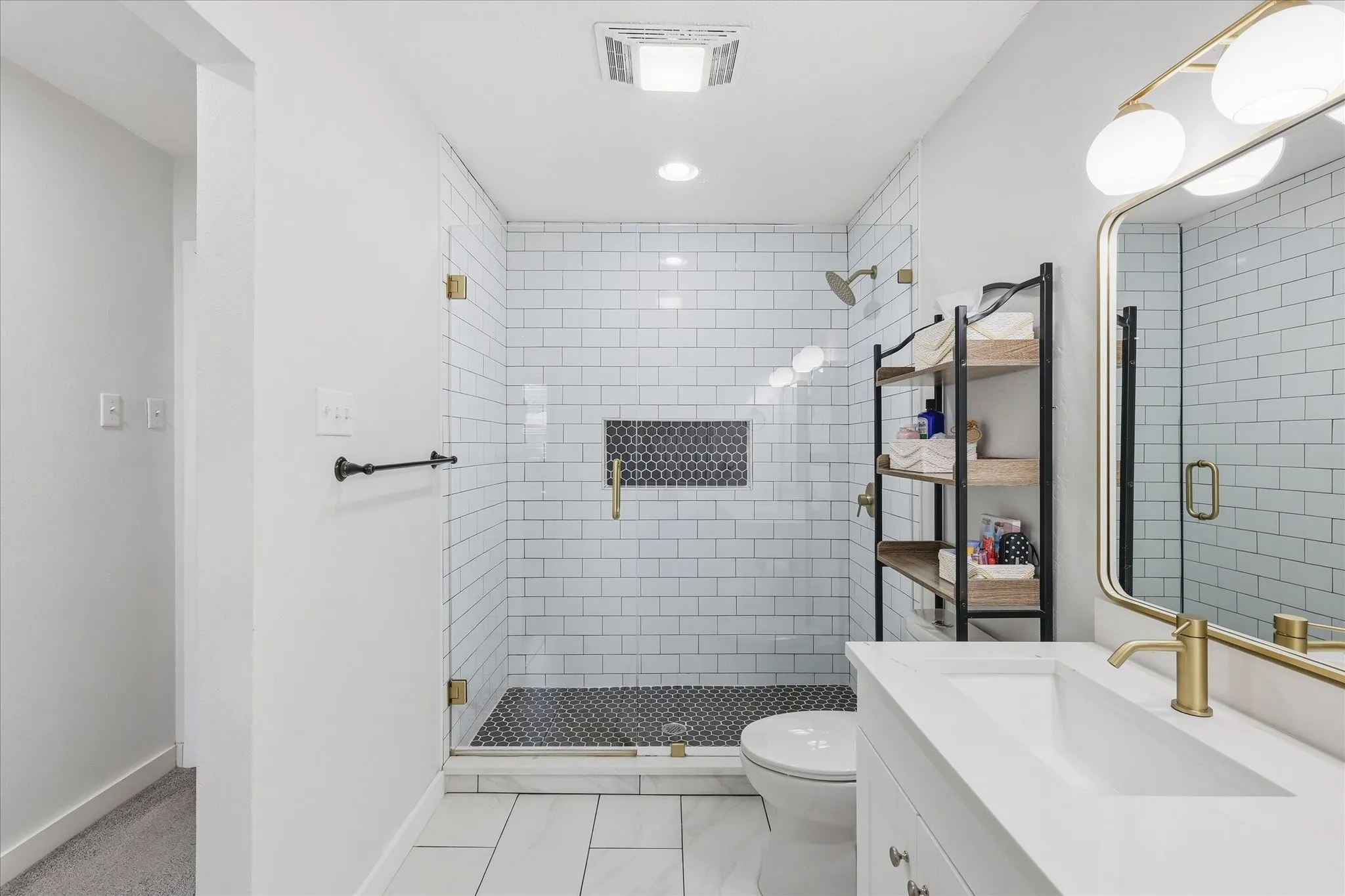 Contemporary bathroom featuring a frameless glass shower enclosure with white subway tile and dark hexagon mosaic accent