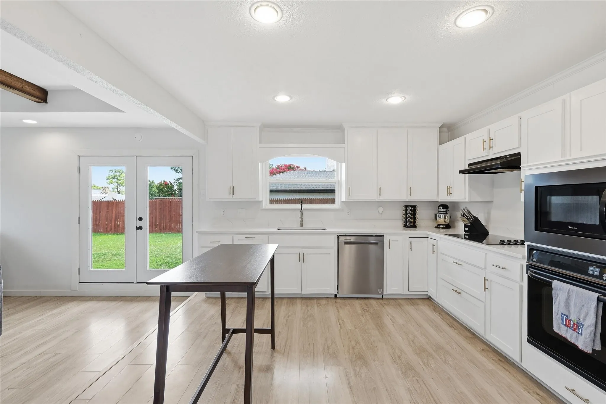 Kitchen featuring white cabinetry, wood-finish flooring, stainless steel appliances, recessed lighting, and a window above the sink