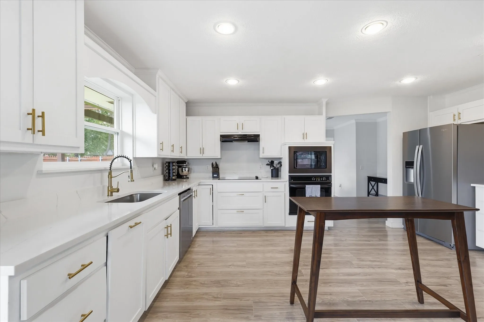 Kitchen featuring white cabinetry with gold-toned hardware, white countertops, wood-finish flooring, a built-in oven with microwave, and recessed lighting