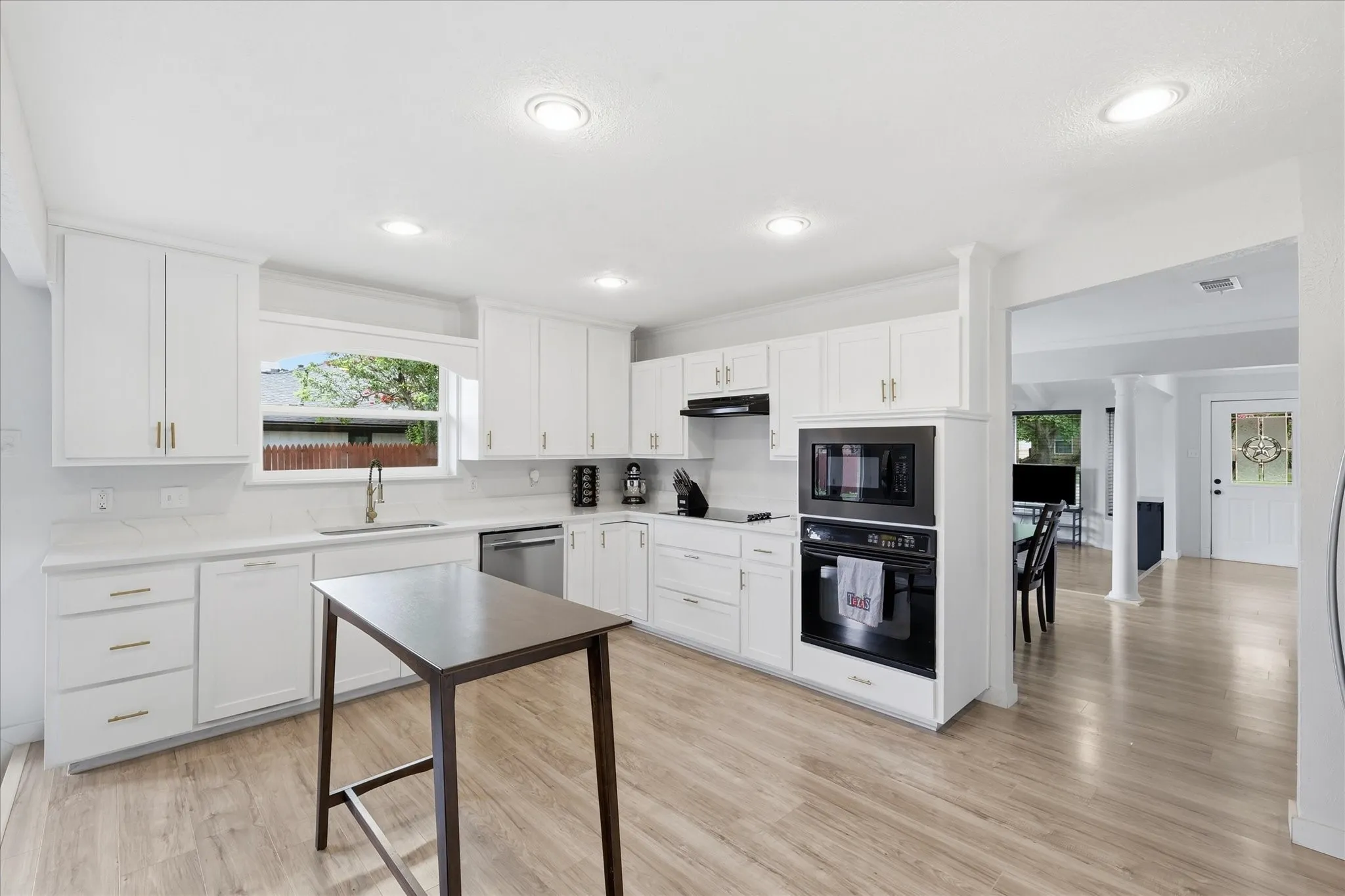 Modern kitchen featuring white cabinetry, light-toned wood-finish flooring, recessed lighting, stainless steel appliances, and quartz countertops with a matching backsplash